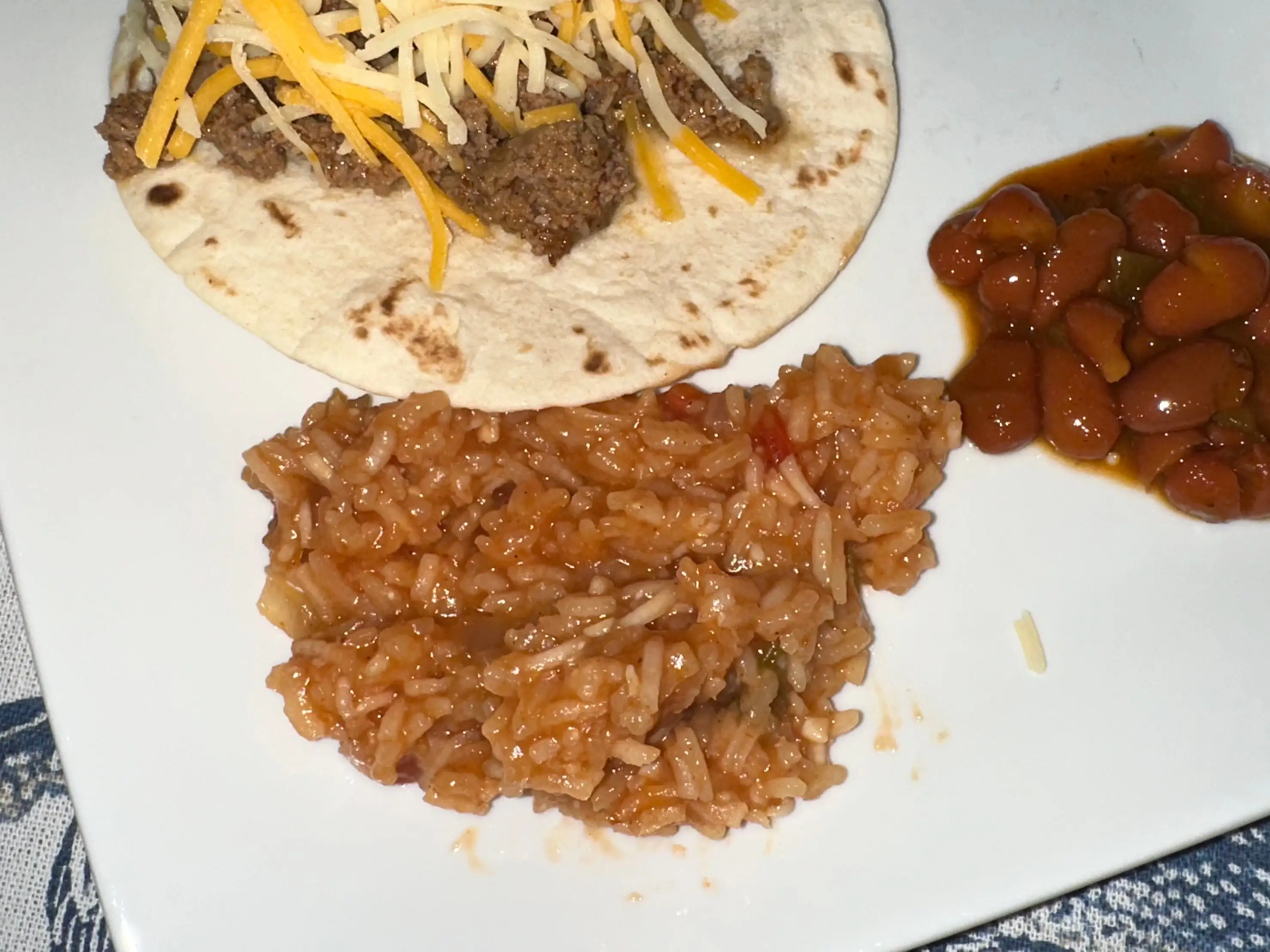 Air-fried taco with beans and Mexican rice on a plate.