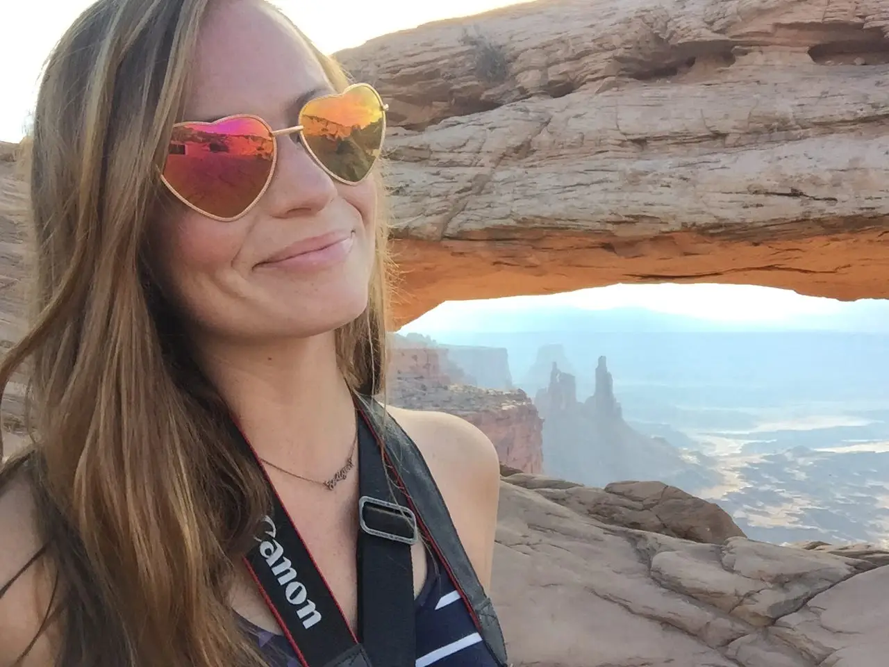 A woman wearing heart-shaped sunglasses posing at Canyonlands National Park.