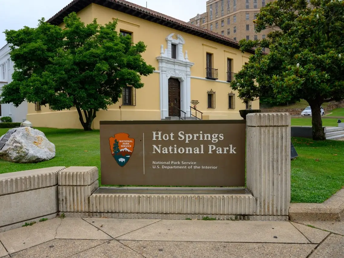 A yellow building and trees behind a sign that reads