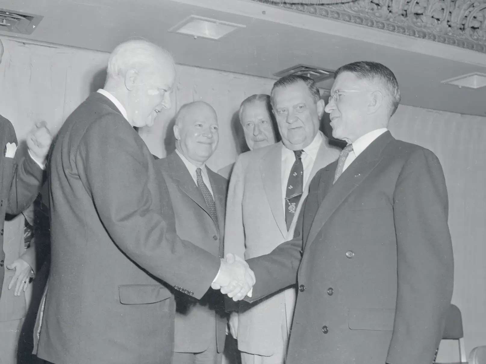 H.L. Hunt (left) shaking hands with Douglas McKay, then Secretary of the Interior, at the 34th annual American Petroleum Institute. Other men stood nearby.