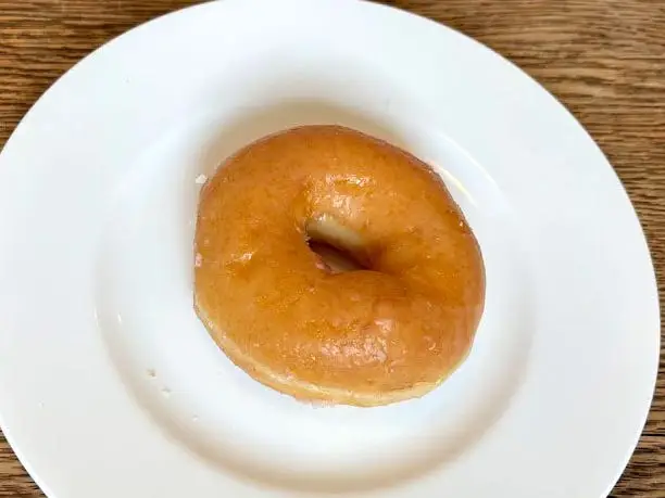 A glazed doughnut on a white plate.