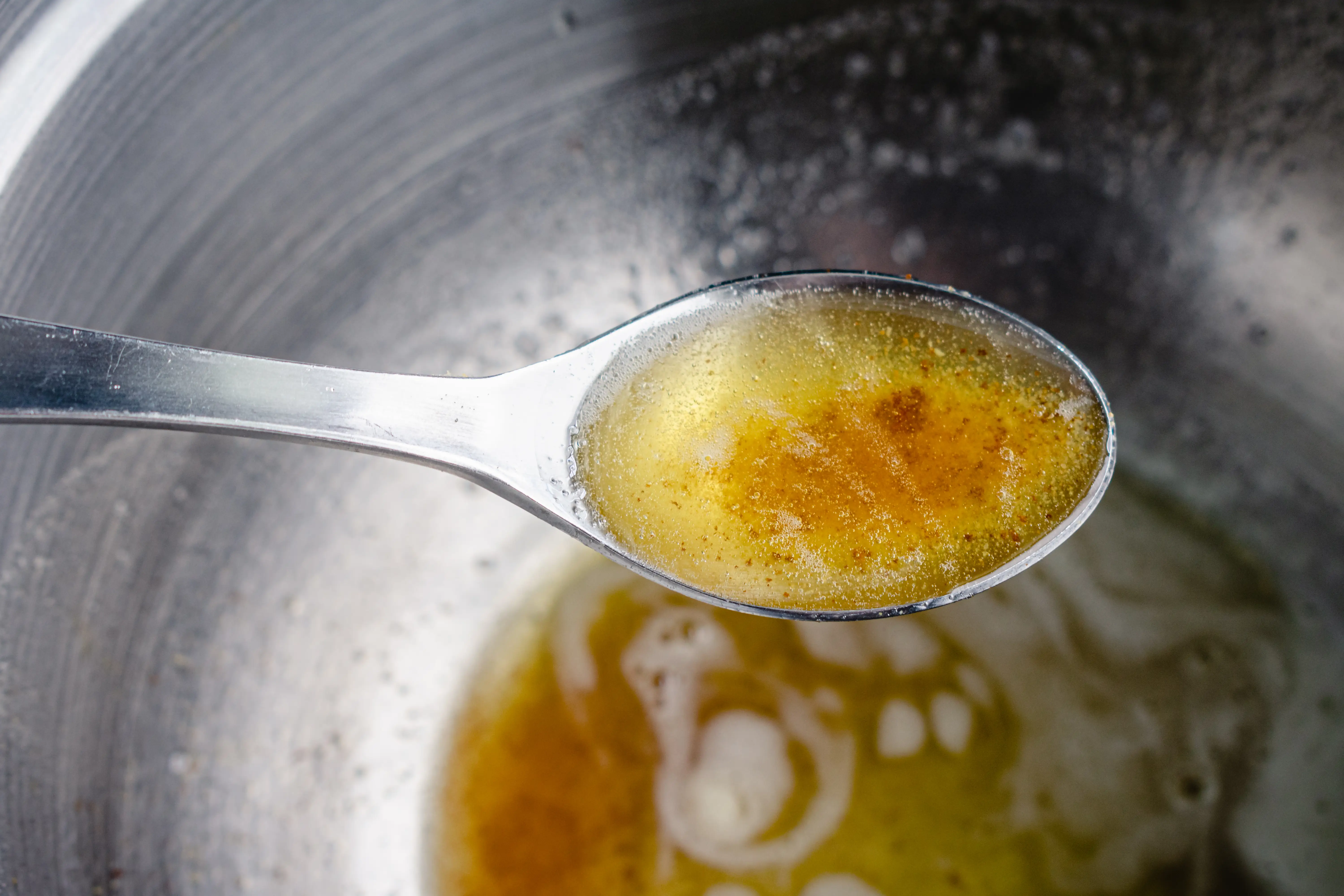 Browned butter in spoon held over mixing bowl
