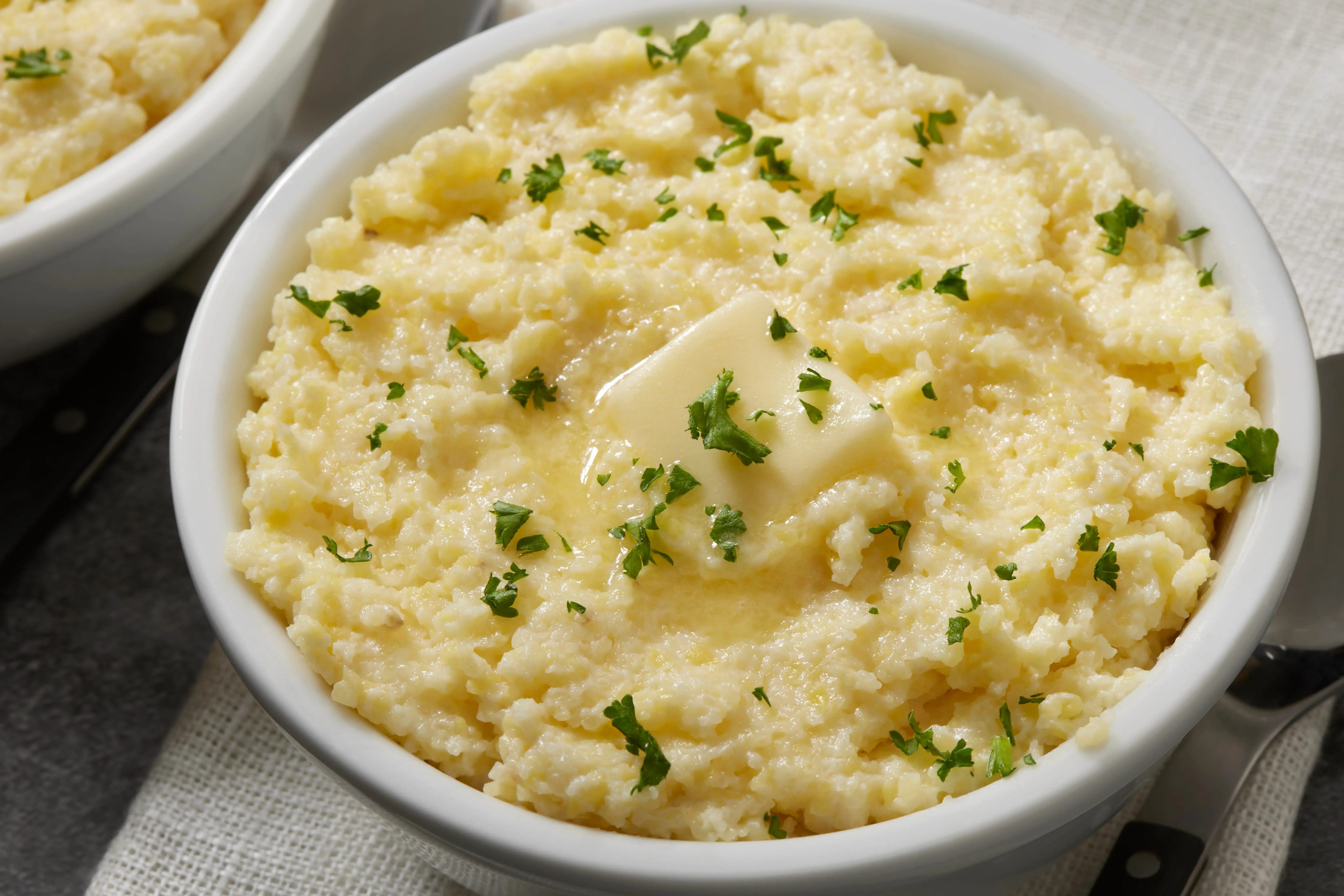 Bowl of mashed potatoes topped with pat of butter and herbs