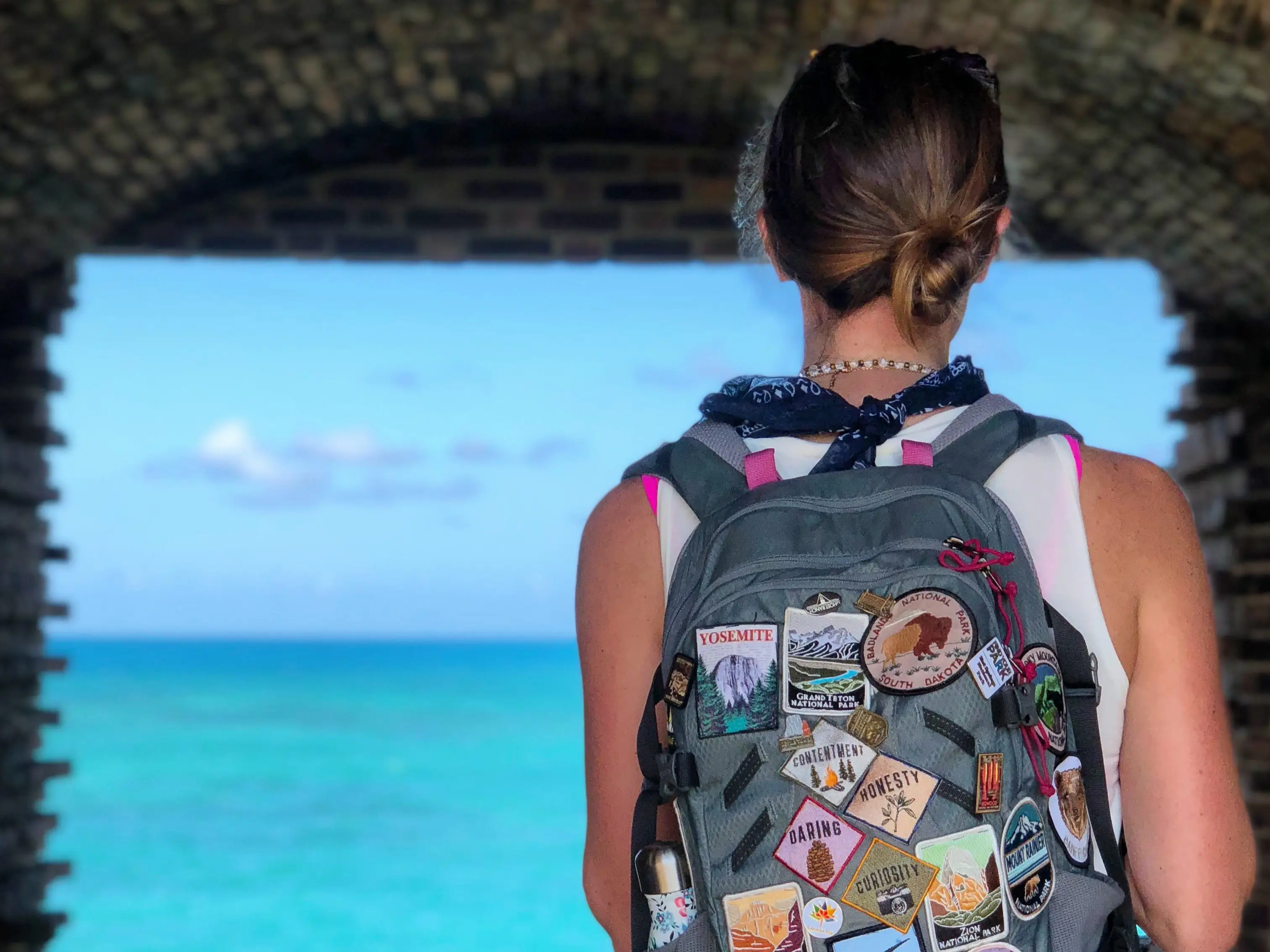 A woman with a backpack looking out at the water at Dry Tortugas National Park.