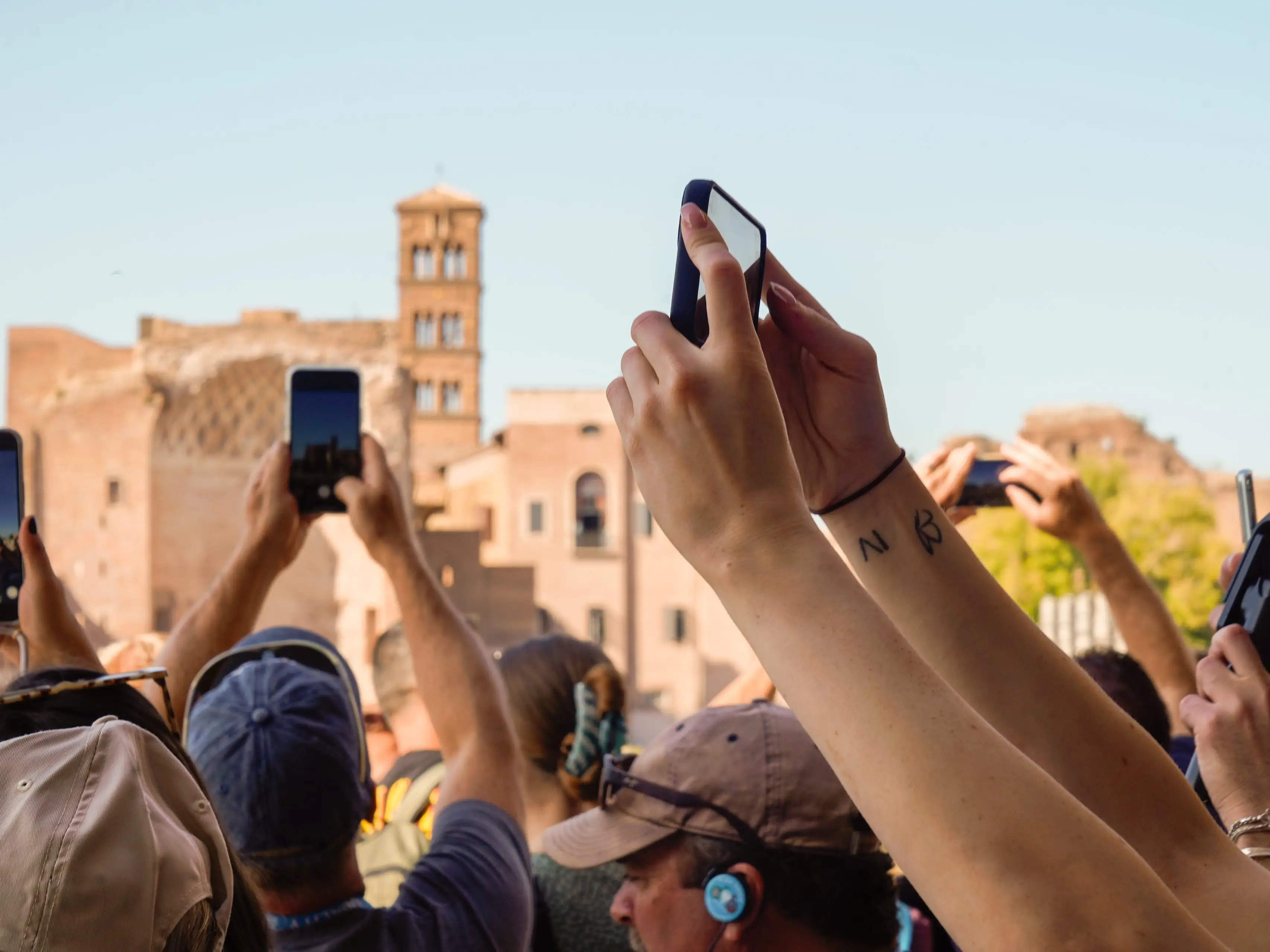 A cluster of arms holding phones to capture a tourist attraction in Rome