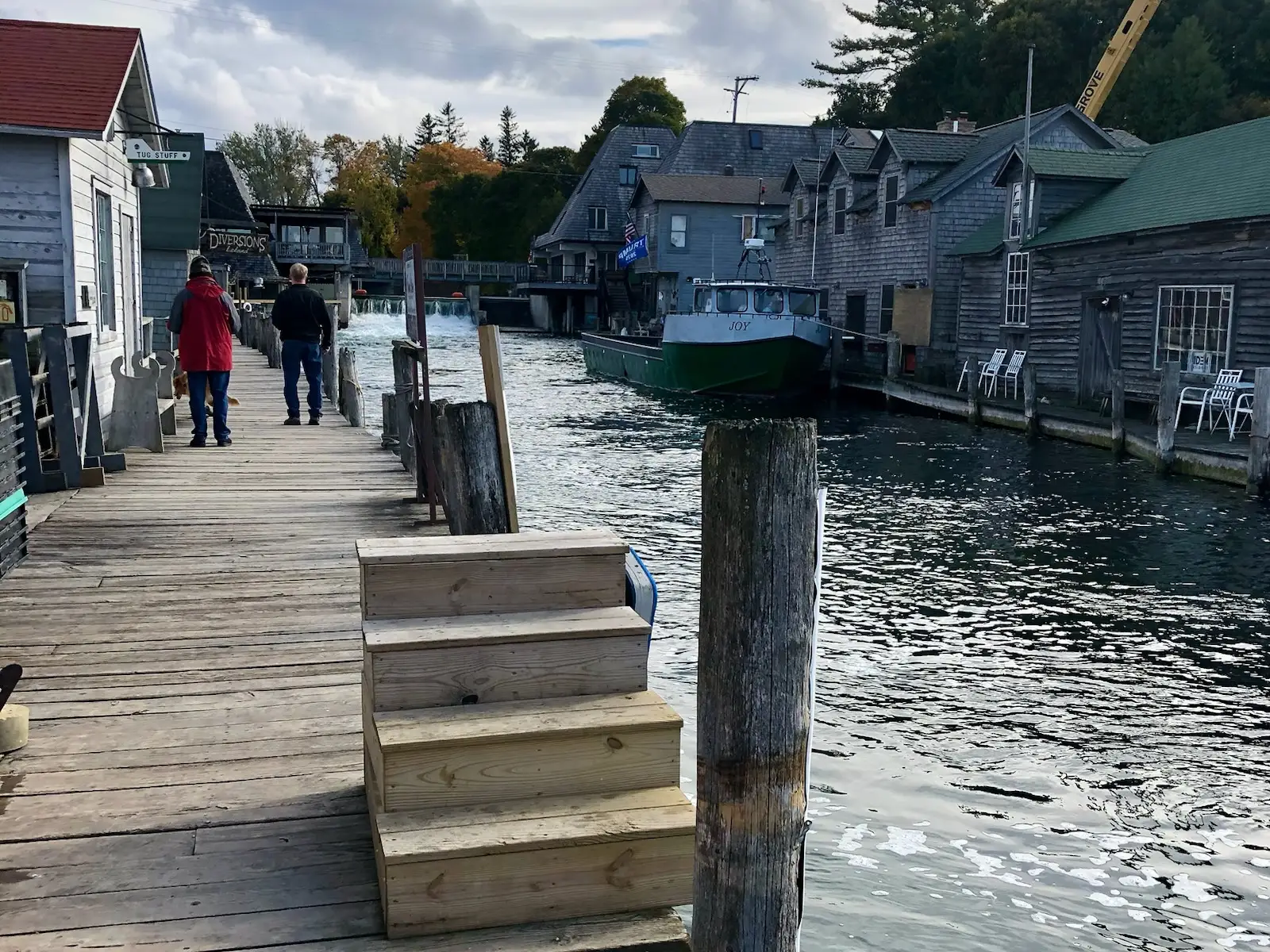 A narrow waterfront walkway in Leland with older-looking buildings on each side.