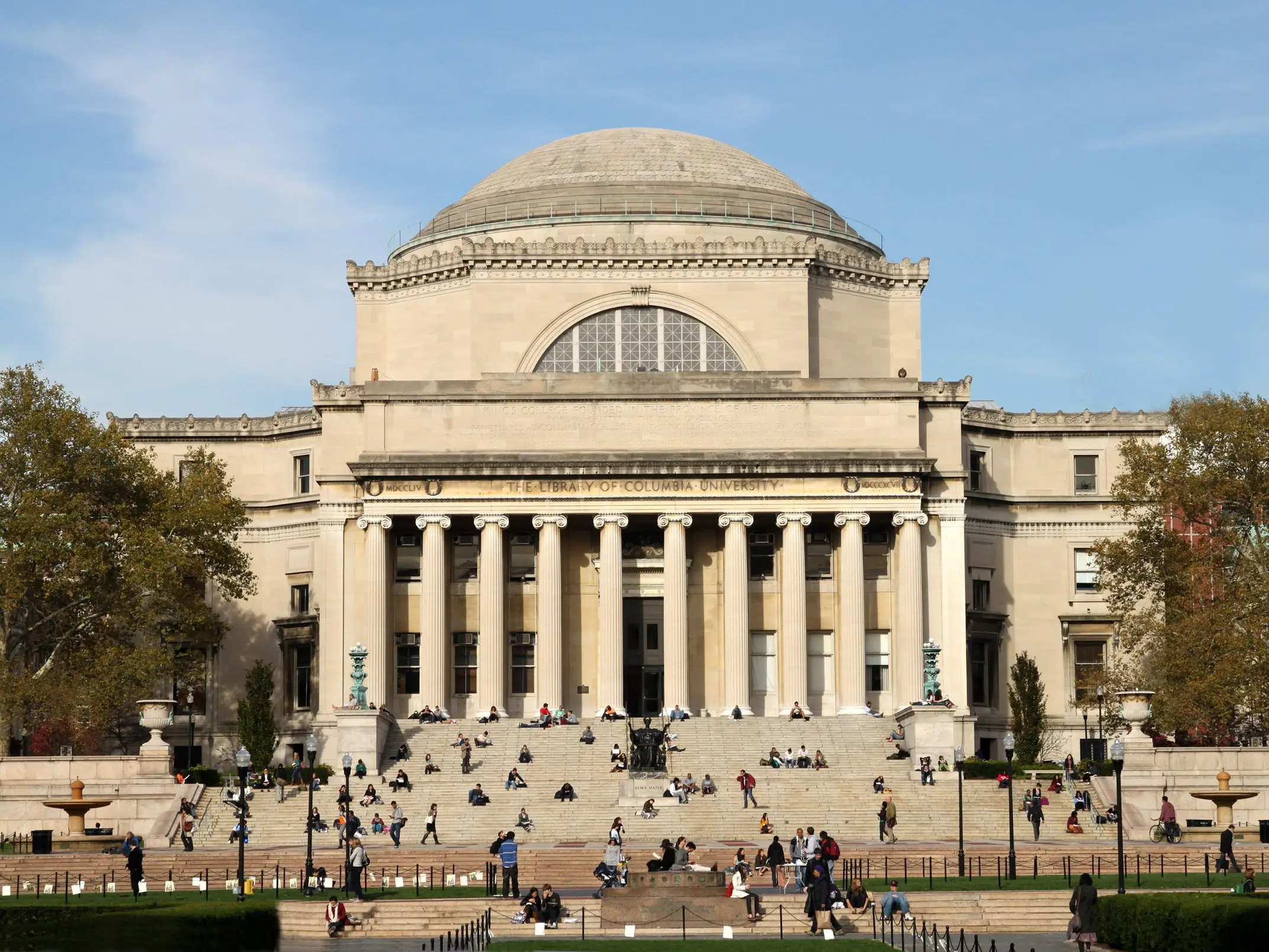 The library of Columbia University, with students sitting on the steps outside.