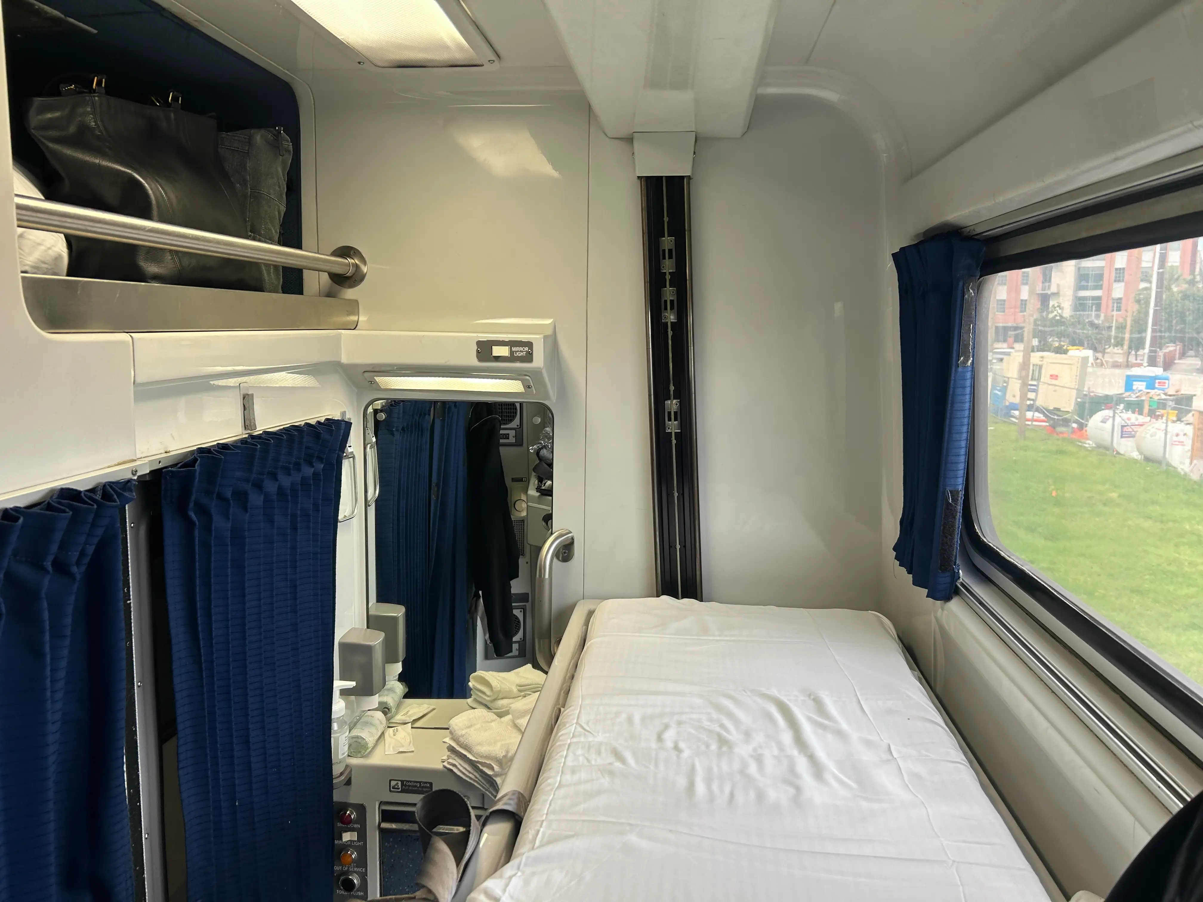 The upper bed in a train roomette next to a higher window.
