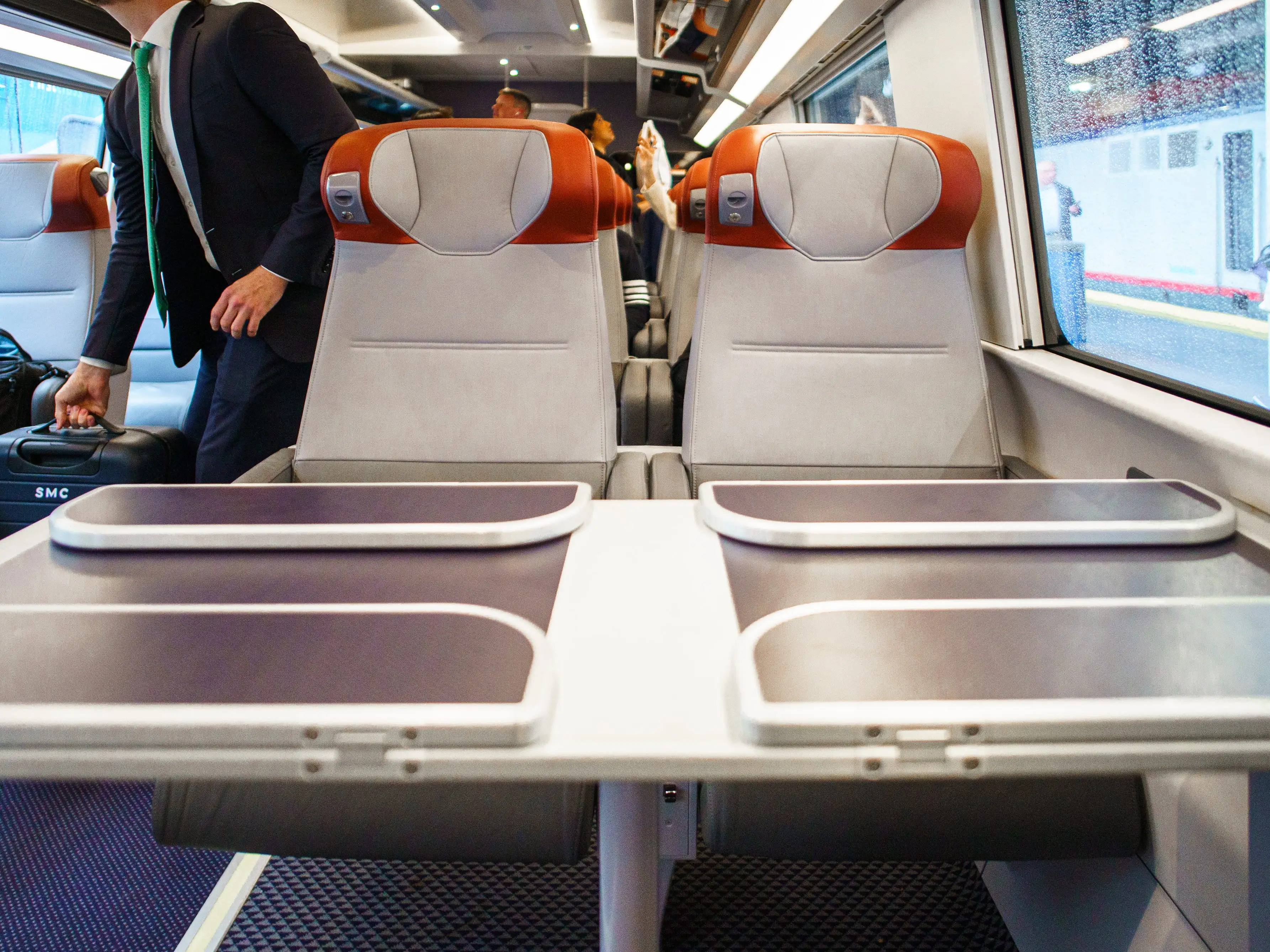 A set of two first-class seats with tables in front of them on an Amtrak Acela train