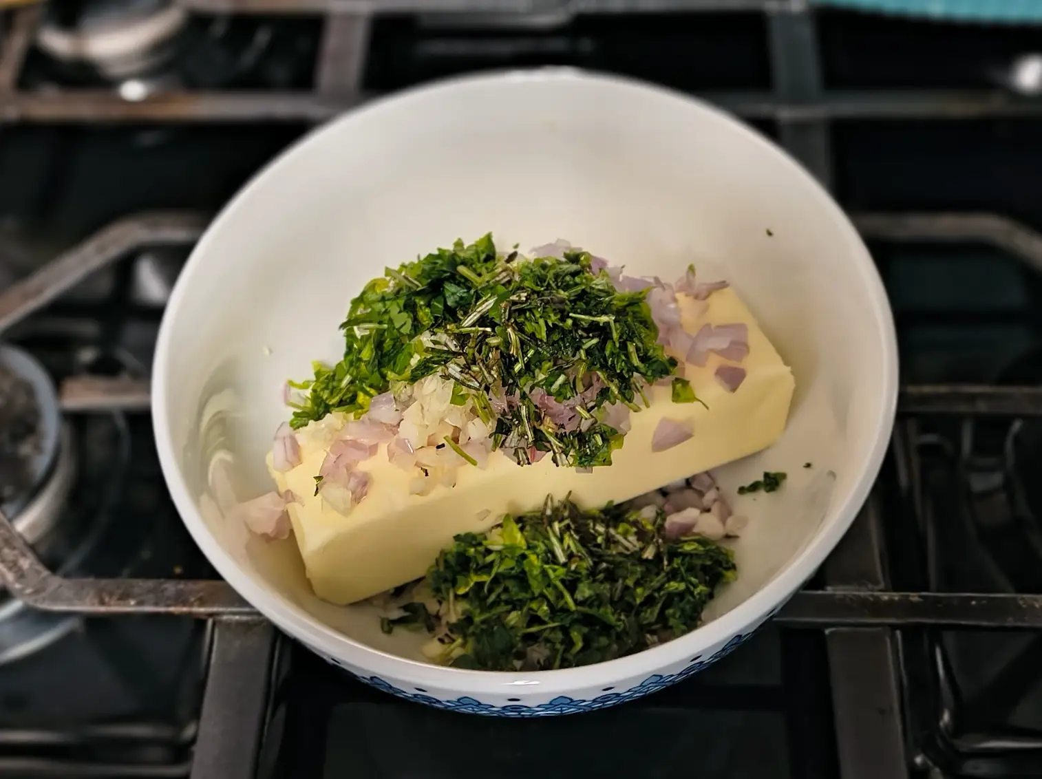 Herbs, onion, and butter mixed together in a bowl.