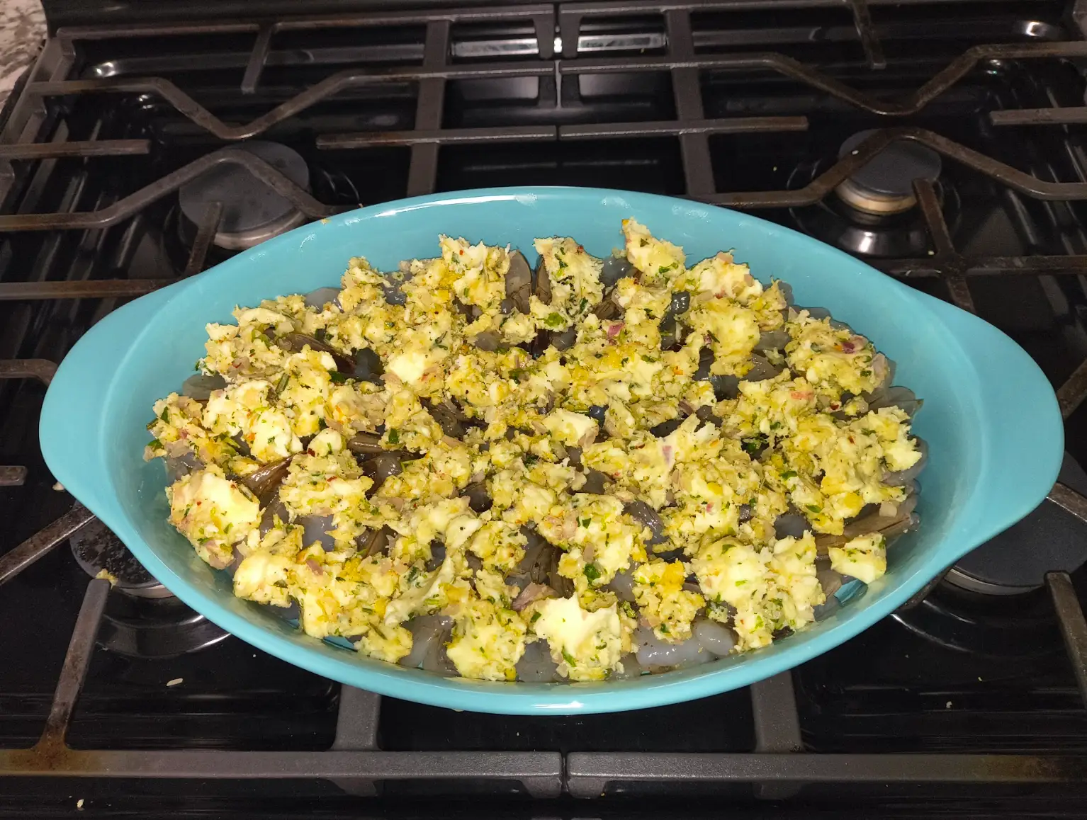 A butter-panko sauce covering shrimp in a dish.