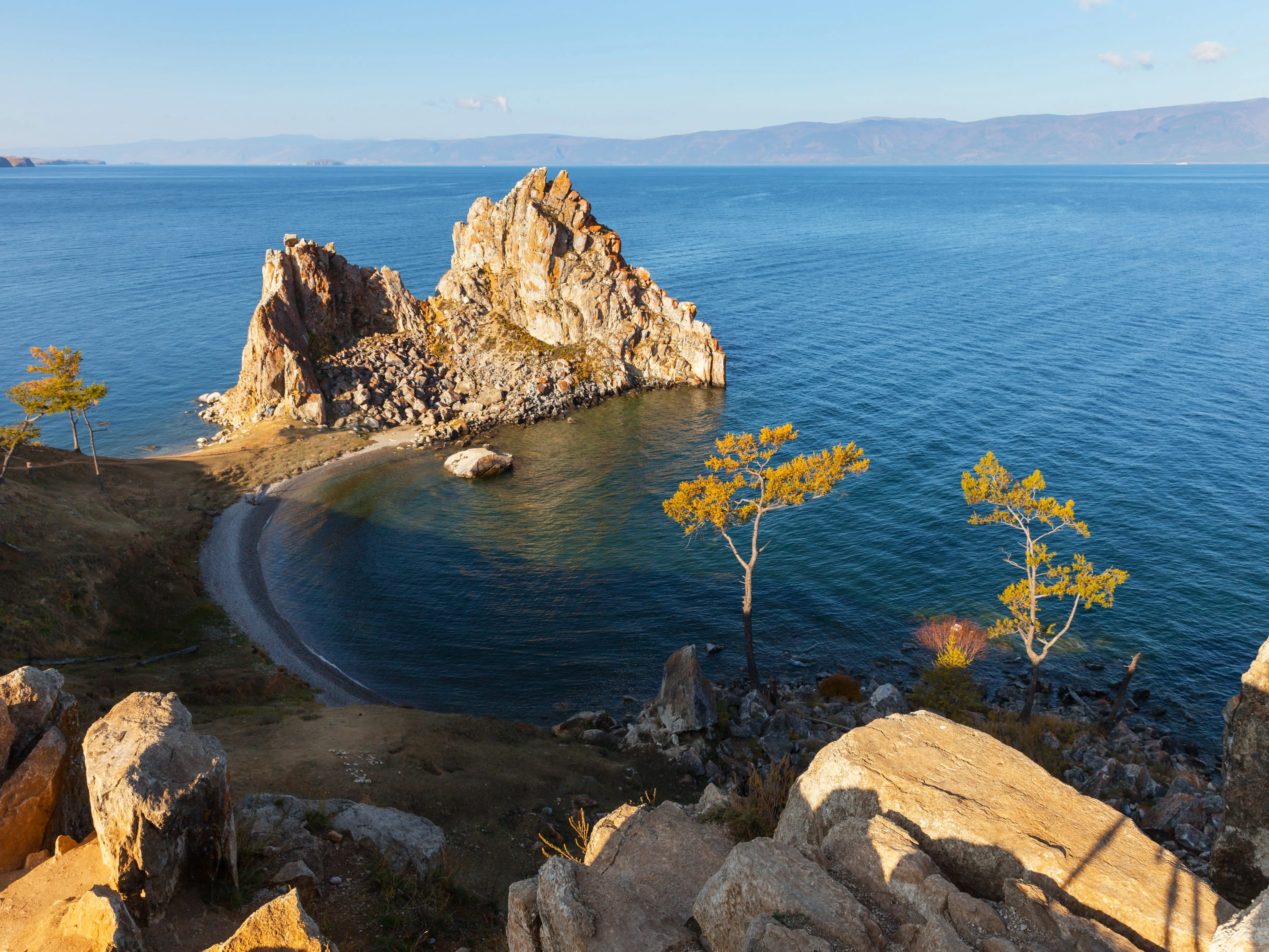 Baikal Lake in Autumn sunny morning. View from rocky Burkhan Cape to famous Shamanka Rock - natural landmark of Olkhon Island on October.