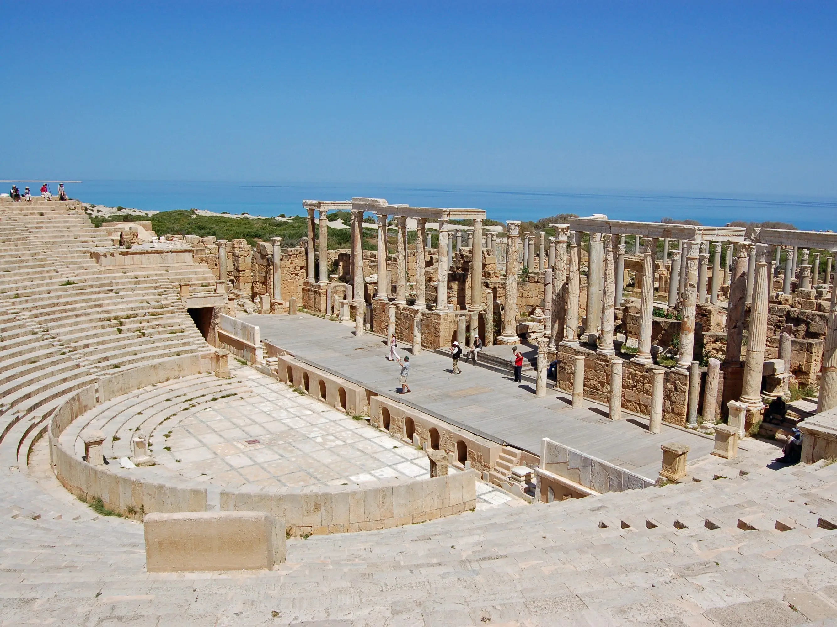 Leptis Magna, Libya. Tourists exploring the ancient Roman theatre overlooking the Mediterranean Sea on the coast of Libya.