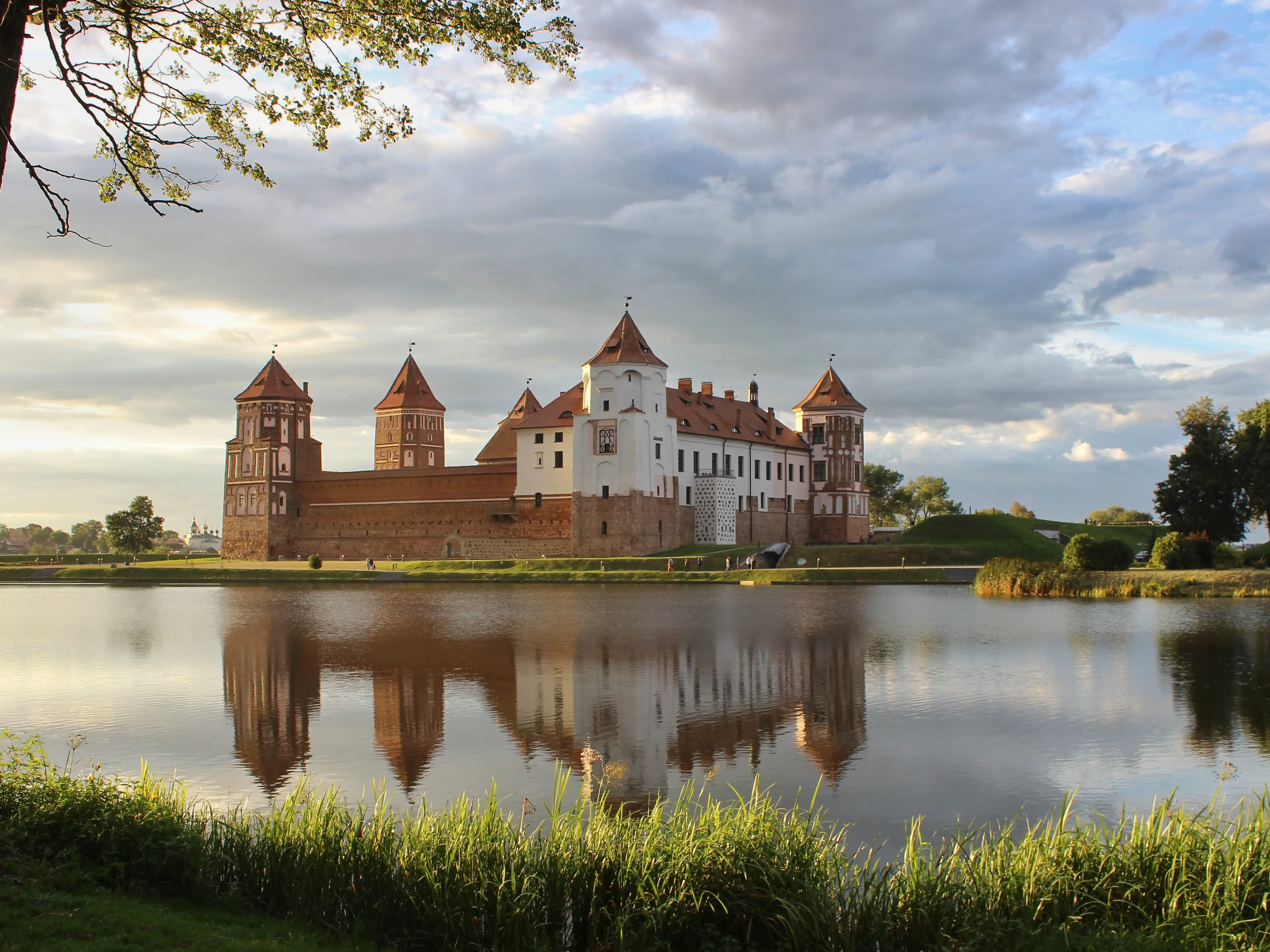 Mir Castle. A castle on the shore of a lake. A summer landscape. Sunset. An ancient medieval fortress. Travel. An architectural monument of the Middle Ages - Mir Castle, Belarus.
