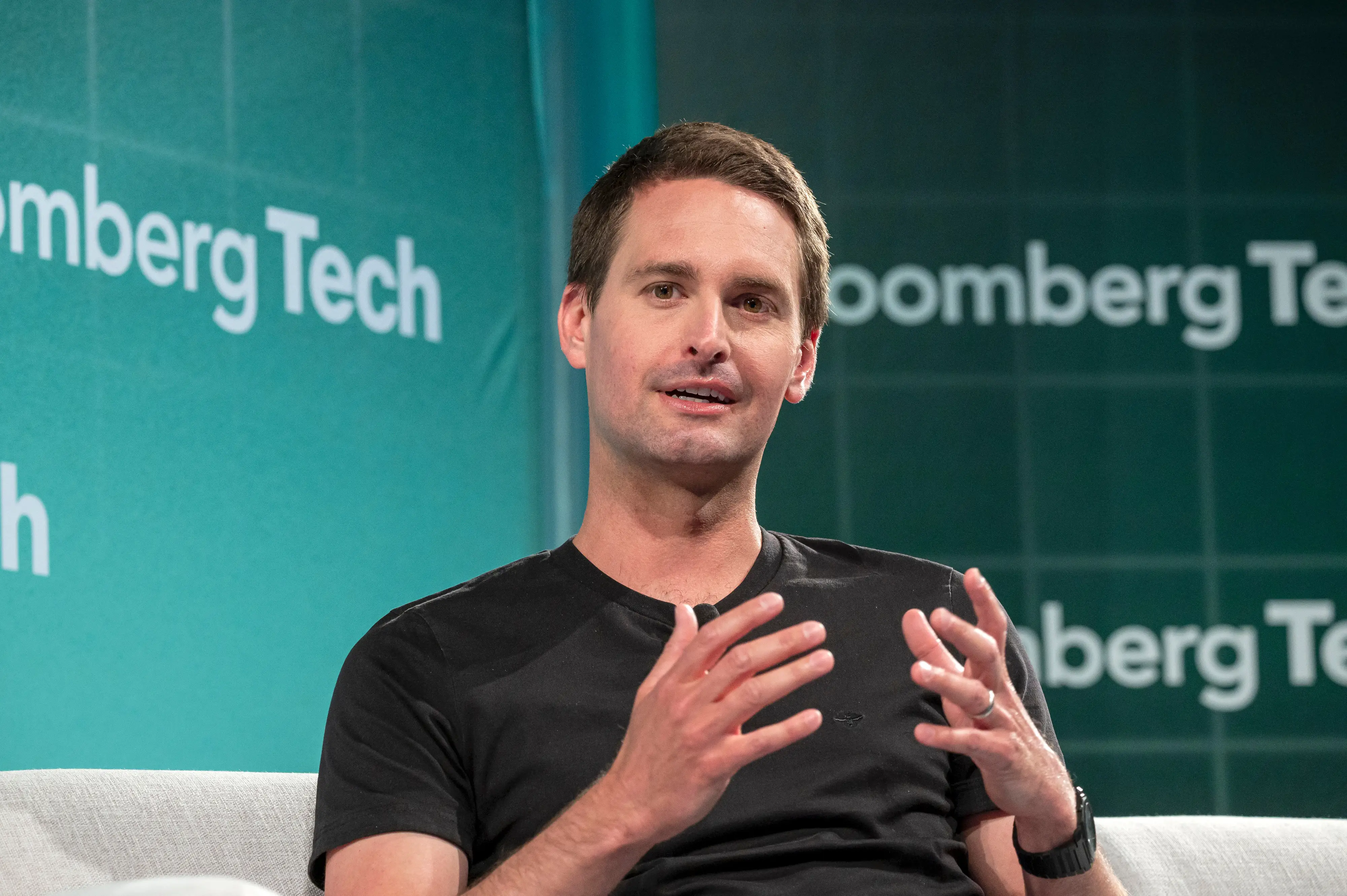 Evan Spiegel, the CEO of Snap, talks onstage. He's wearing a black T-shirt and a black watch.