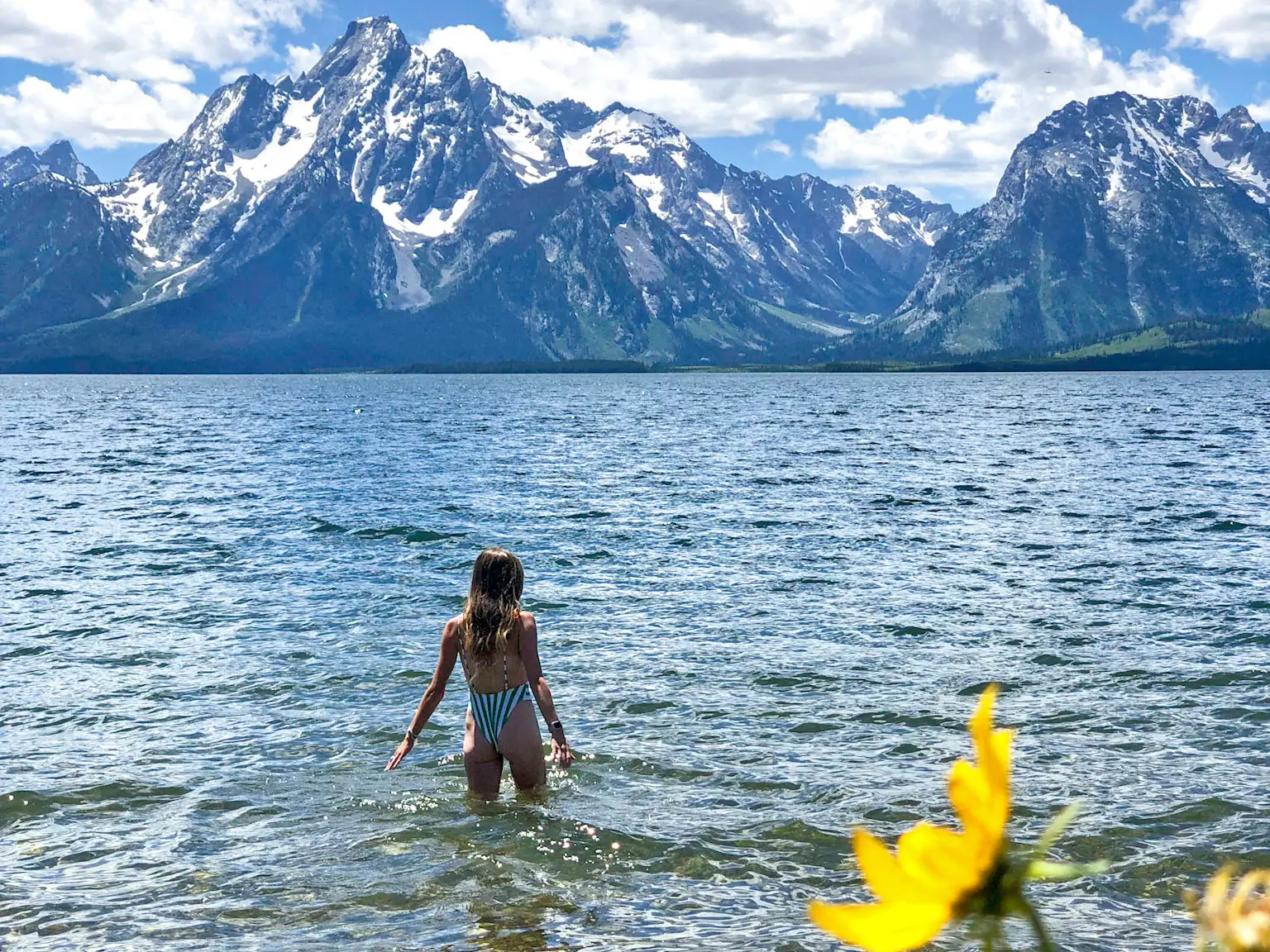 Emily stands in the water at Grand Teton National Park, with mountains in the background.