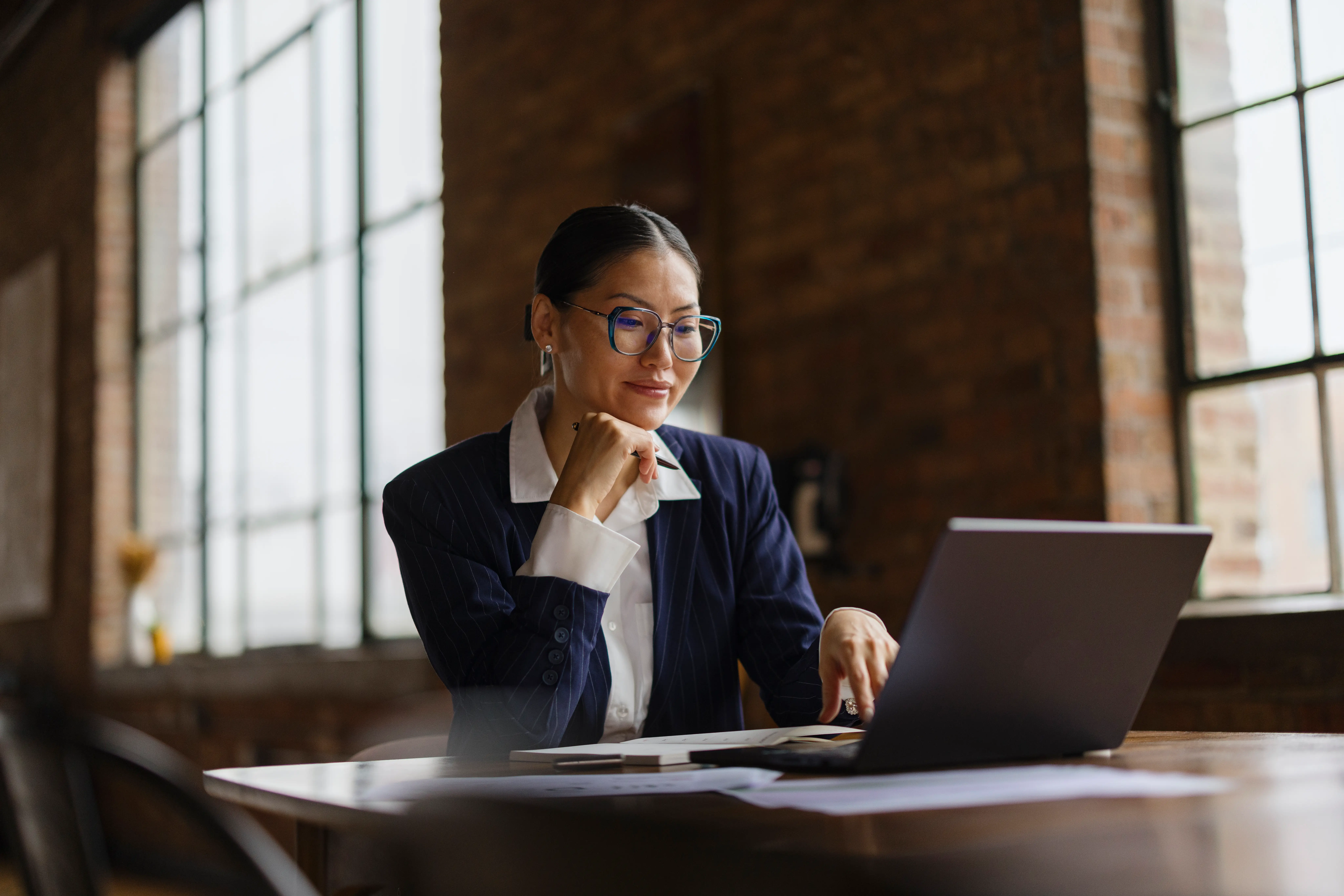 A person wearing glasses and business attire using a laptop