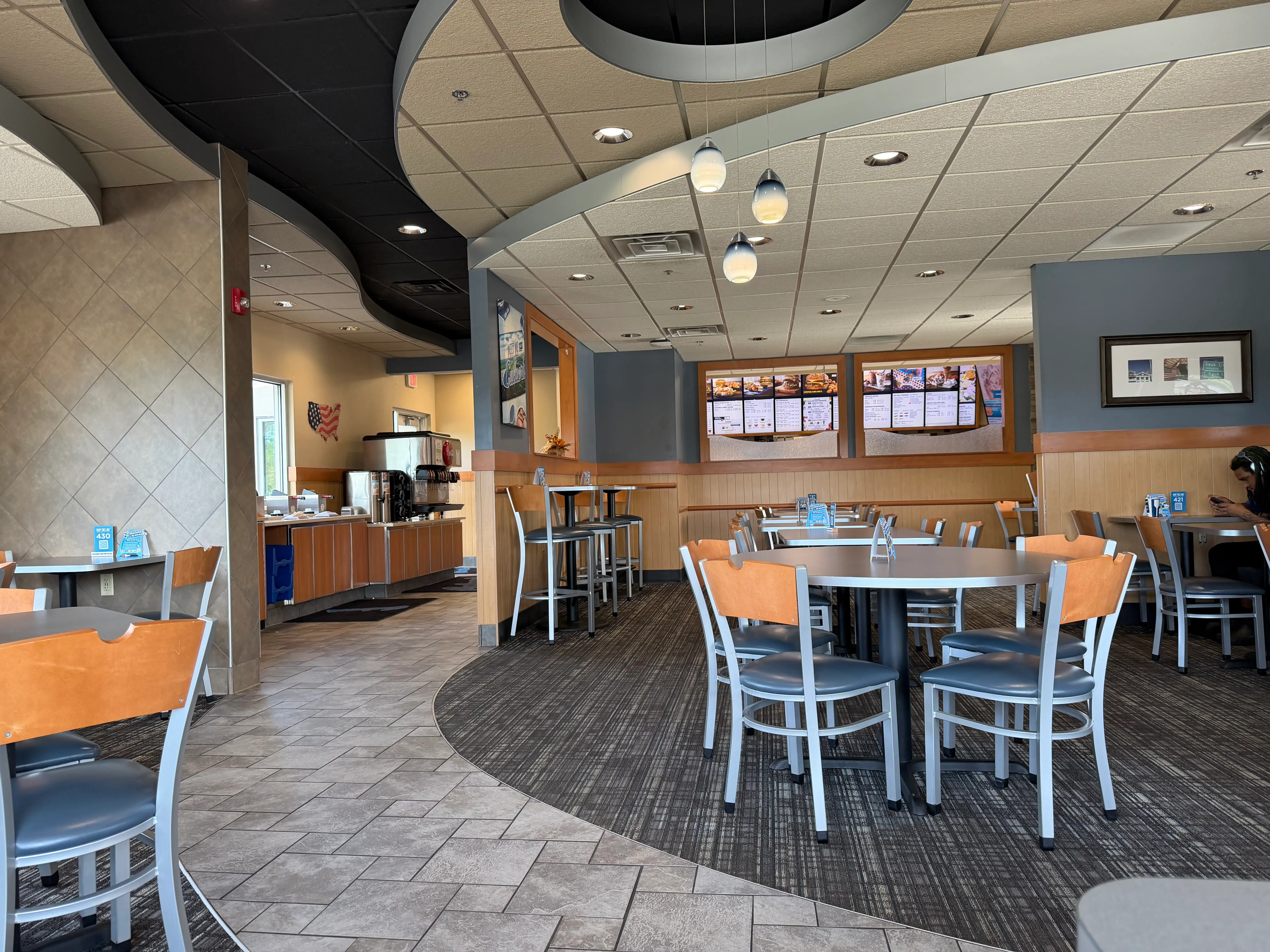 Interior of an empty Culver's with gray tile, patterned carpet, and minimal decor