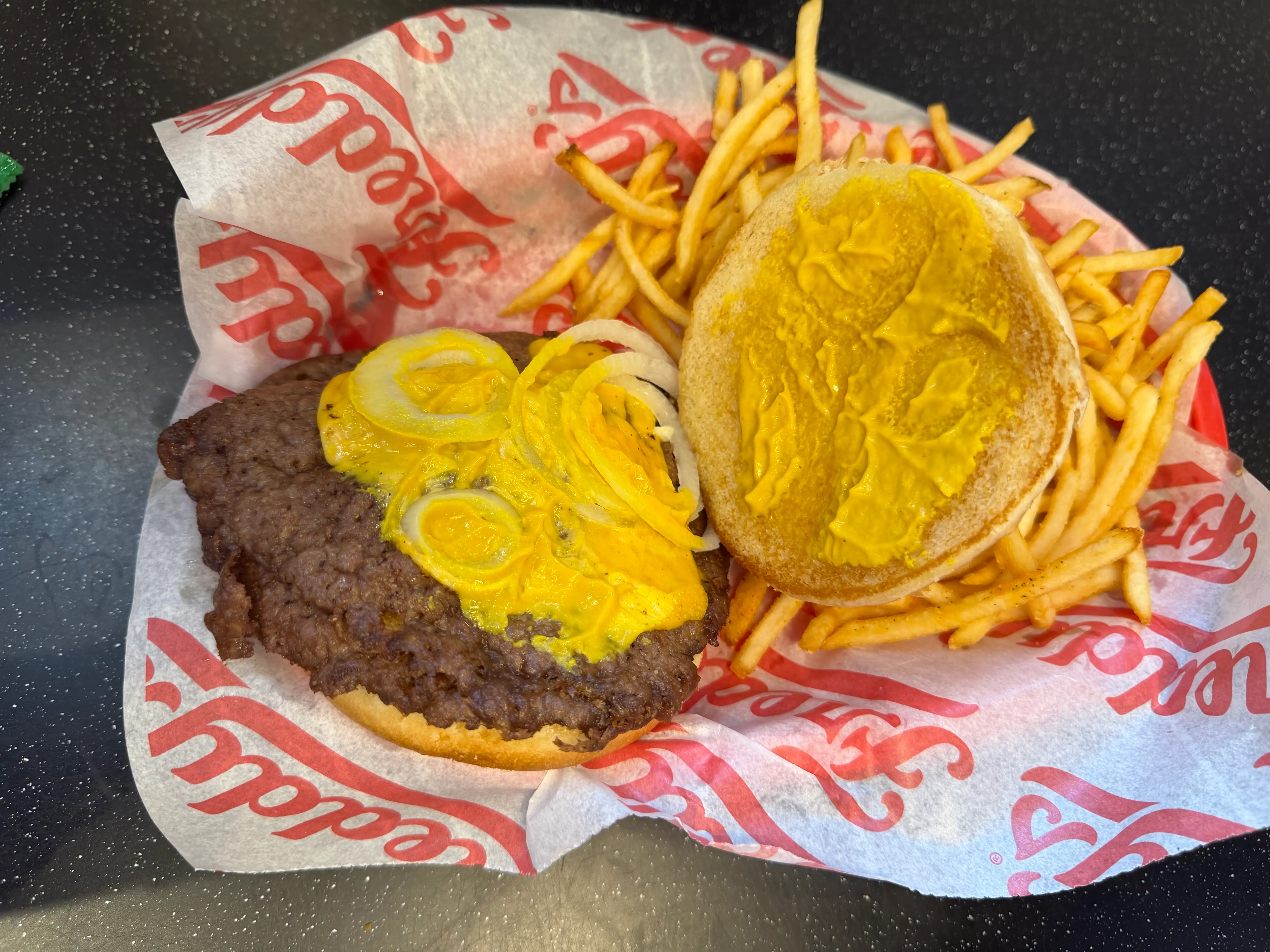 Burger at Freddys with bun removed, showing yellow sauce and a few onions