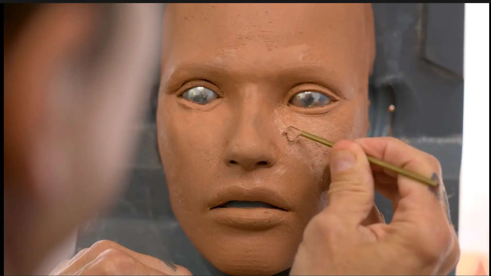 A person scraping texture onto a humanoid face.