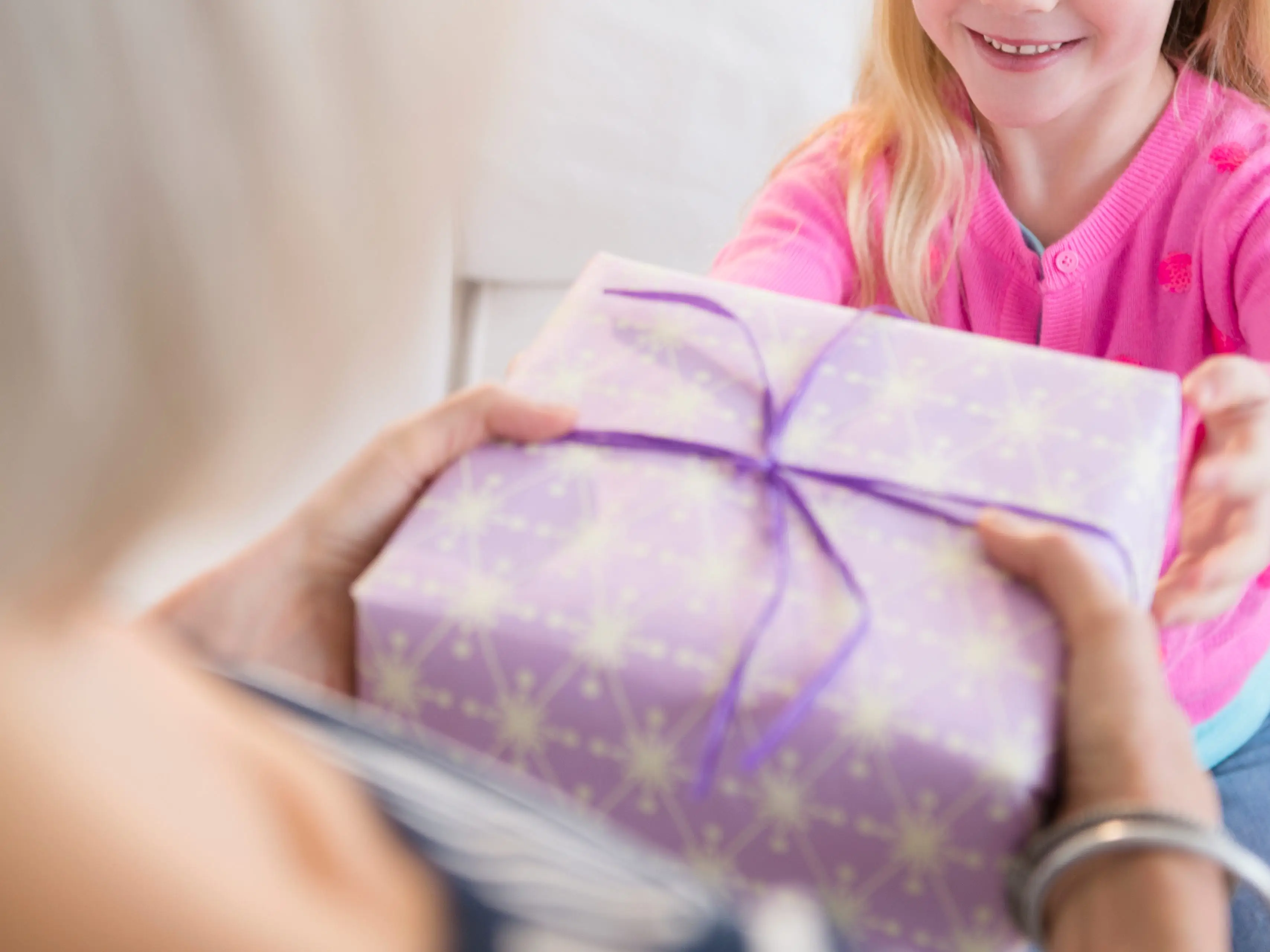 An older woman handing a gift to a child.