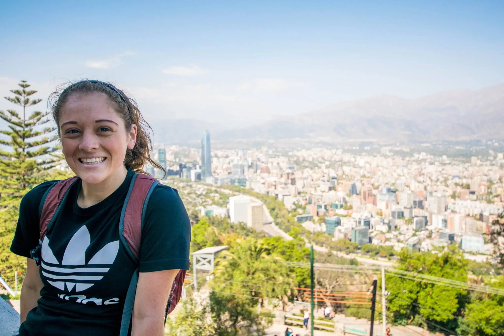 Author Jenna DeLaurentis smiling next to aerial view of buildings, trees in Chile