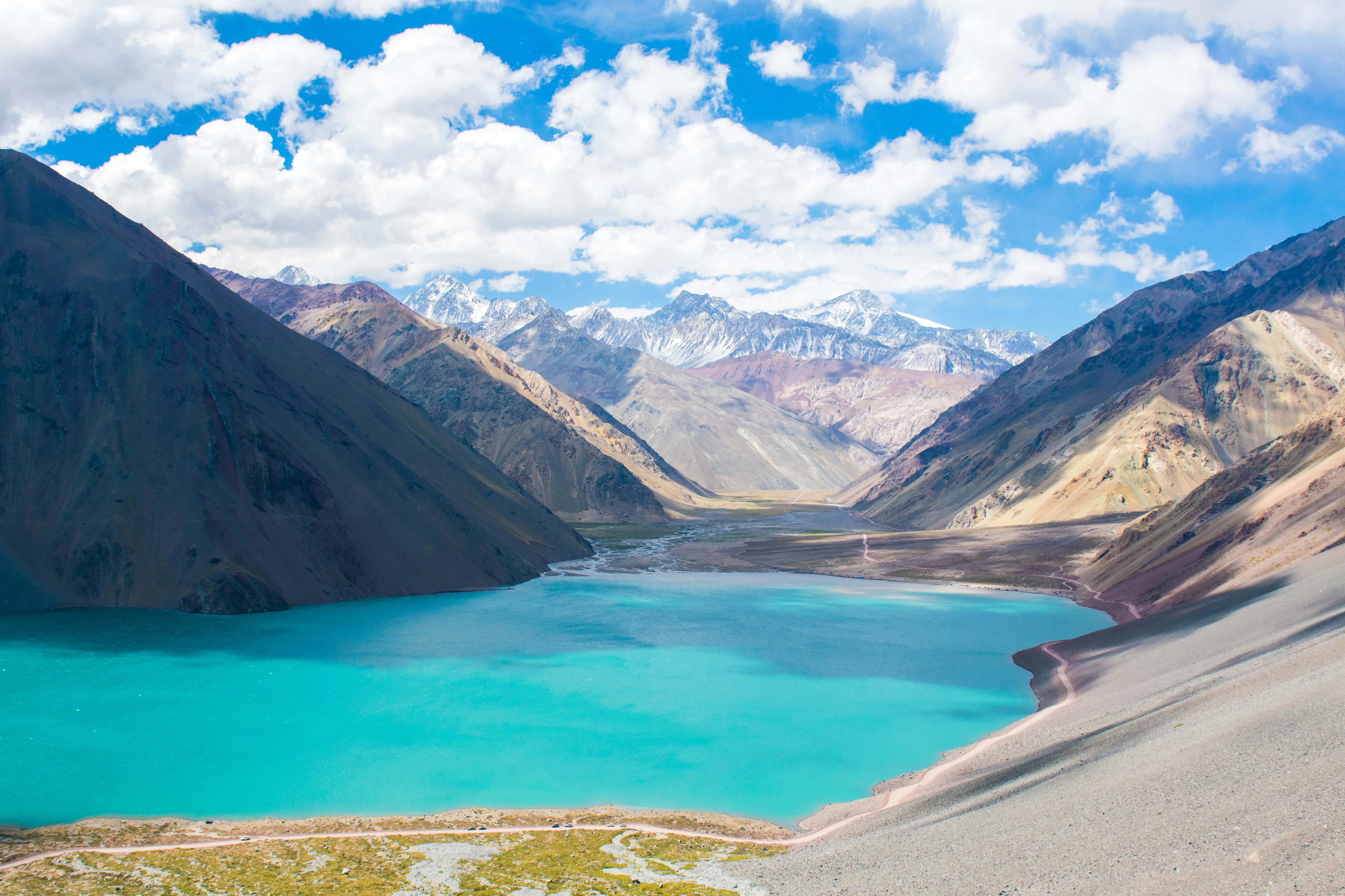 View of bright blue wate surrounded by mountains under cloudy skiy