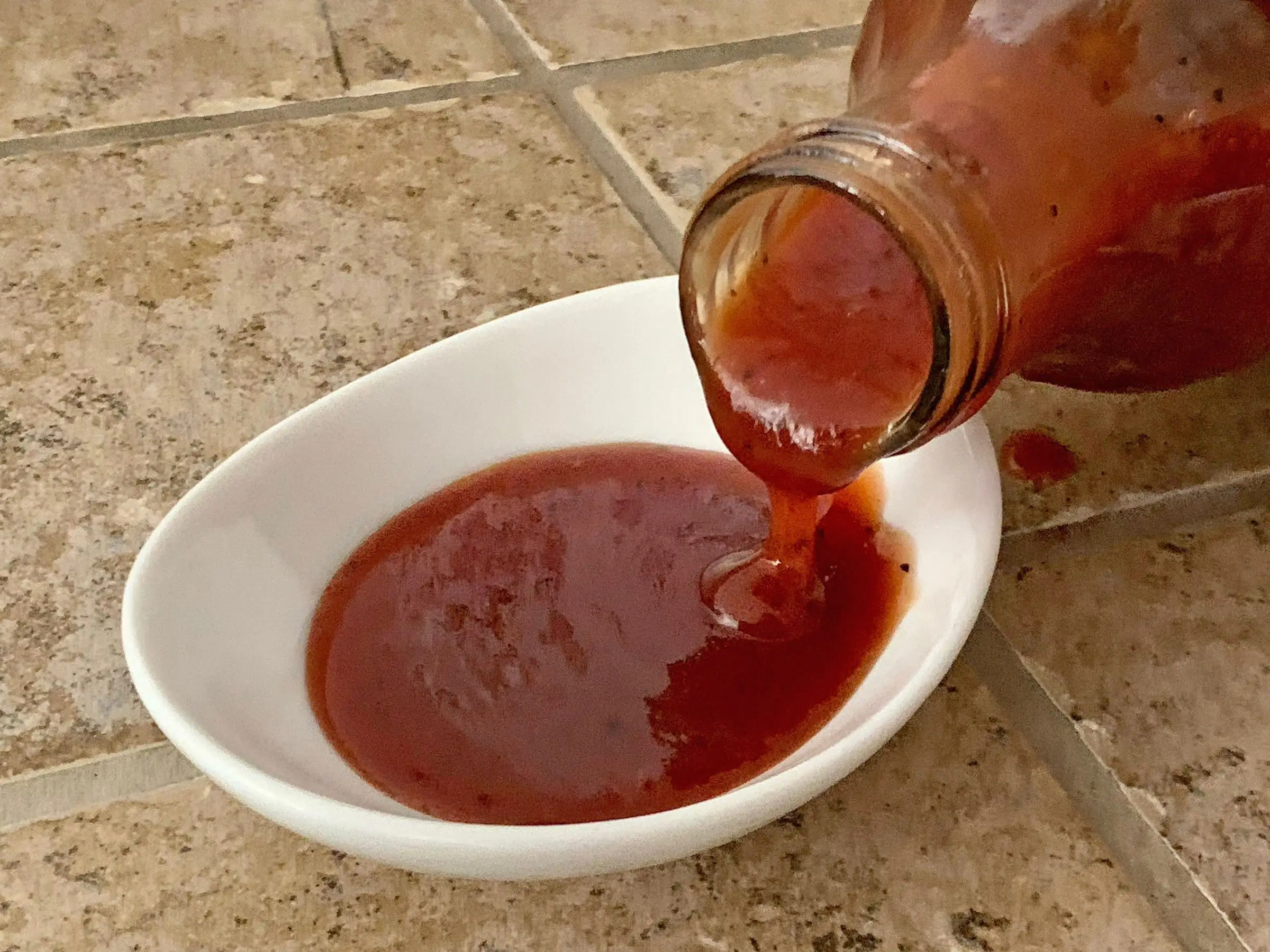 Trader Joe's pineapple barbecue sauce being poured into a small white bowl.