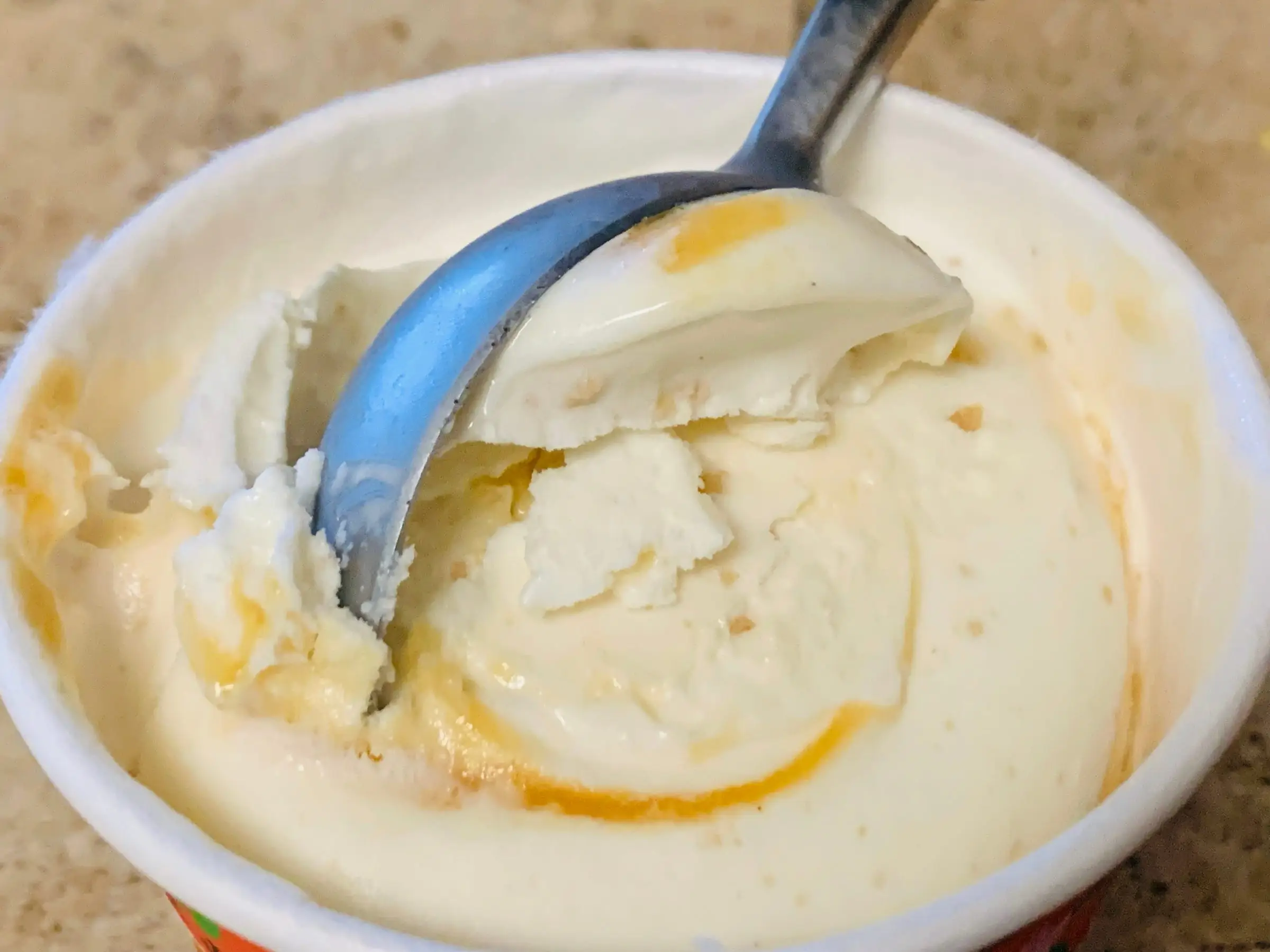Trader Joe's peach-crisp ice cream getting scooped out of the carton.
