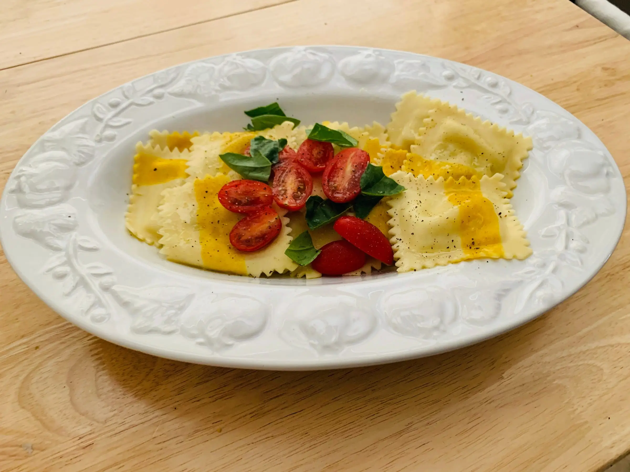 Trader Joe's sweet corn and burrata ravioli served on a white plate and garnished with cherry tomatoes and basil.