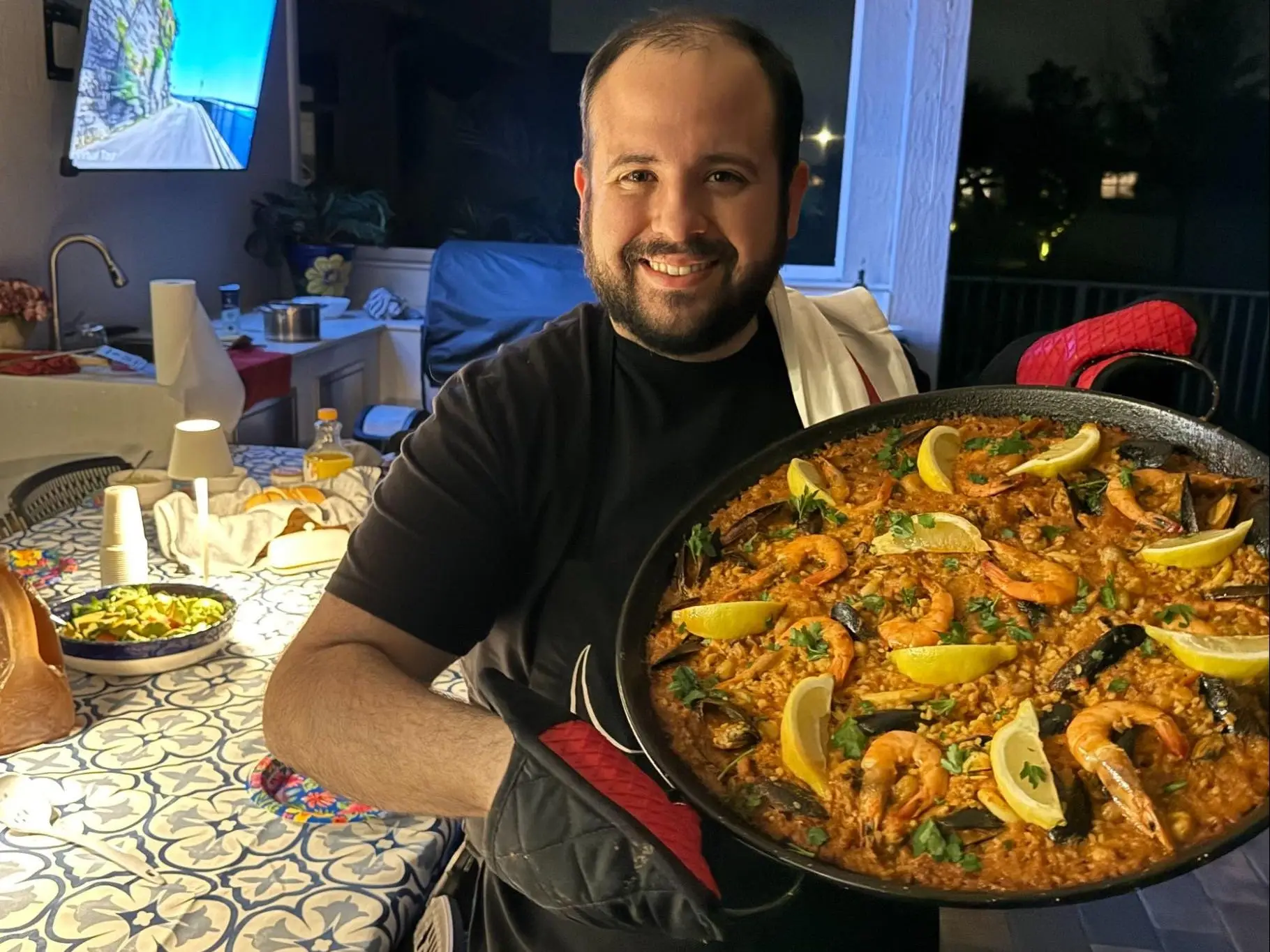 John Paul Hernandez holding up a large pan of paella