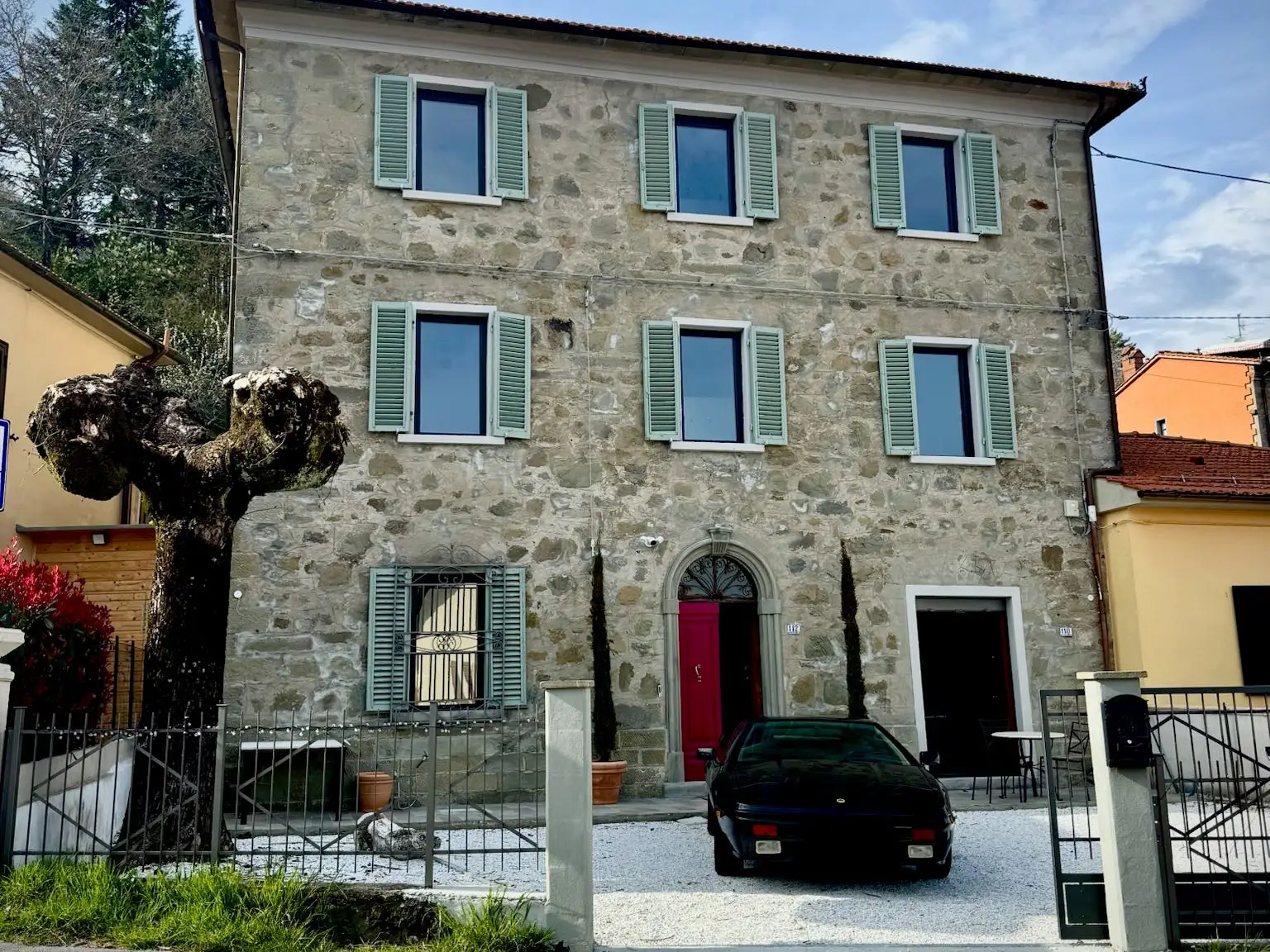 View of stone villa with black car out front, red front door