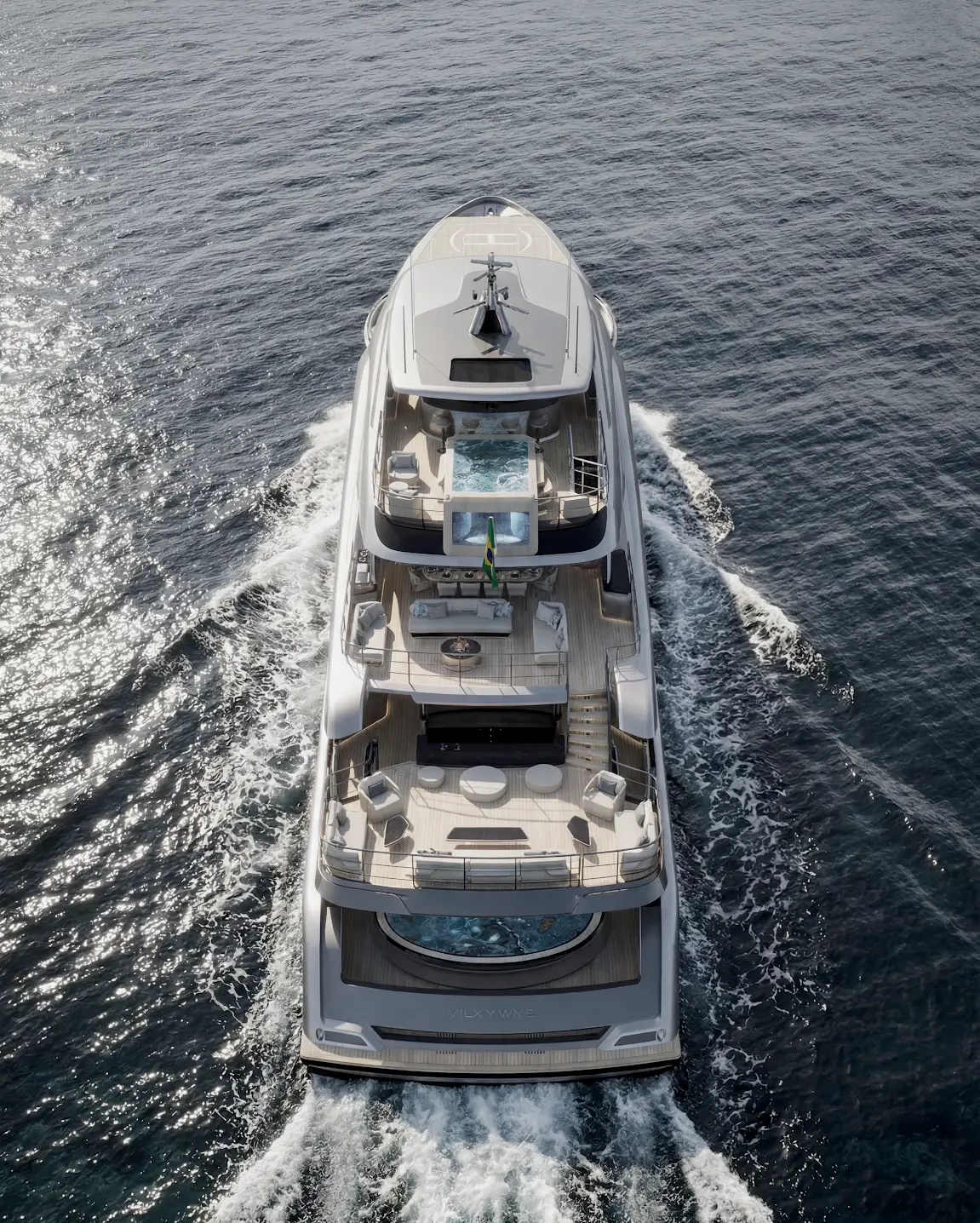 Aerial view of a large luxury yacht cruising through open water with wake trails and sun glare.