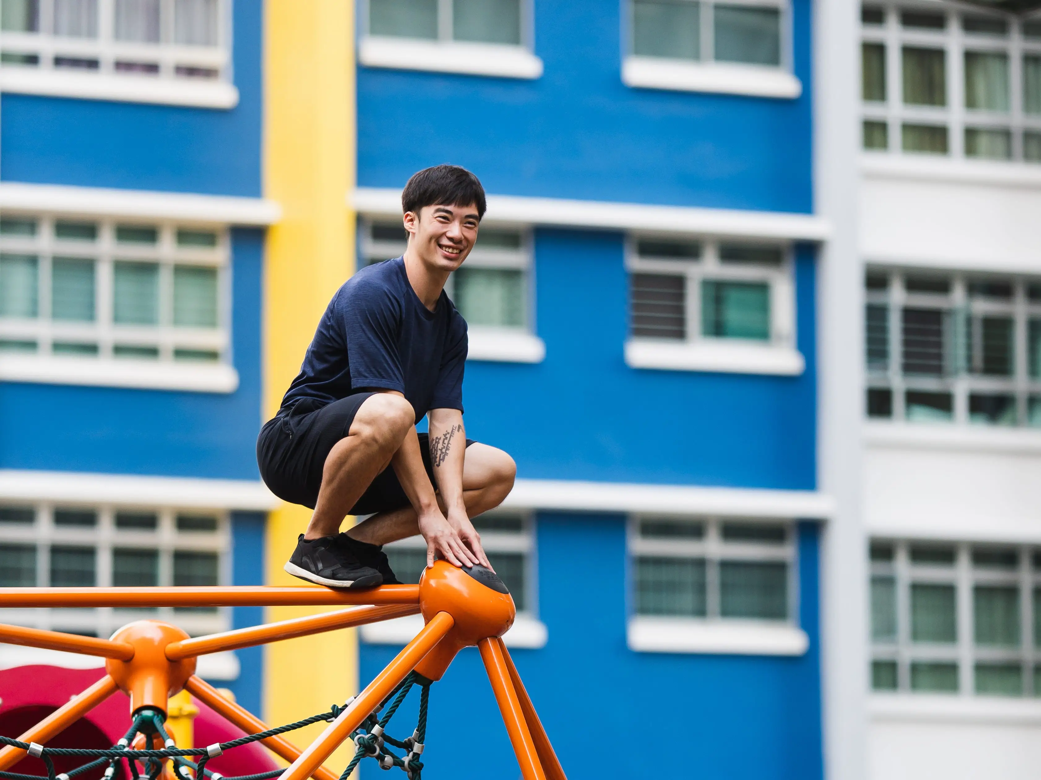 A man balancing on a playground structure in Singapore.