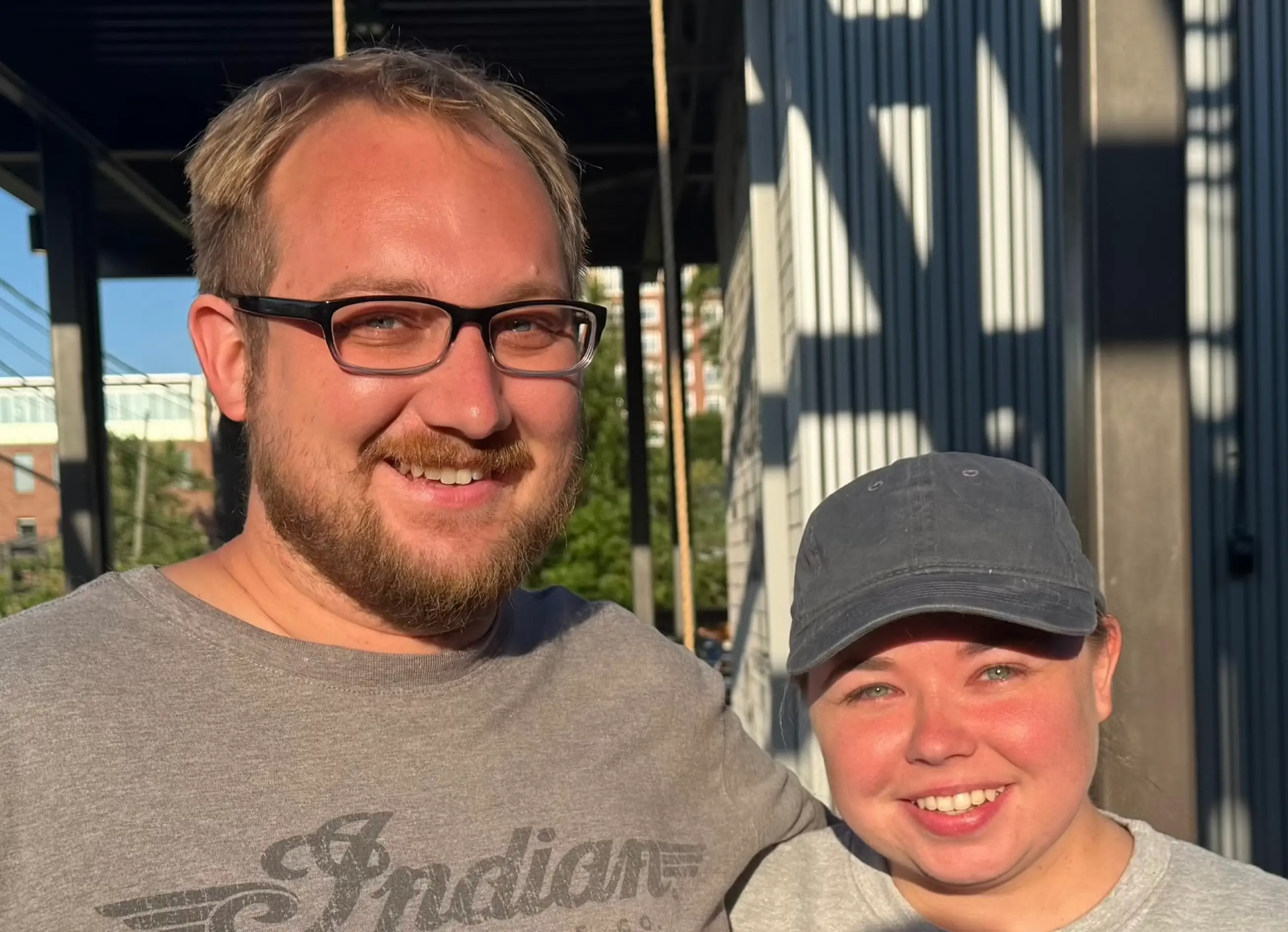 Man with glasses and woman with hat on smiling together