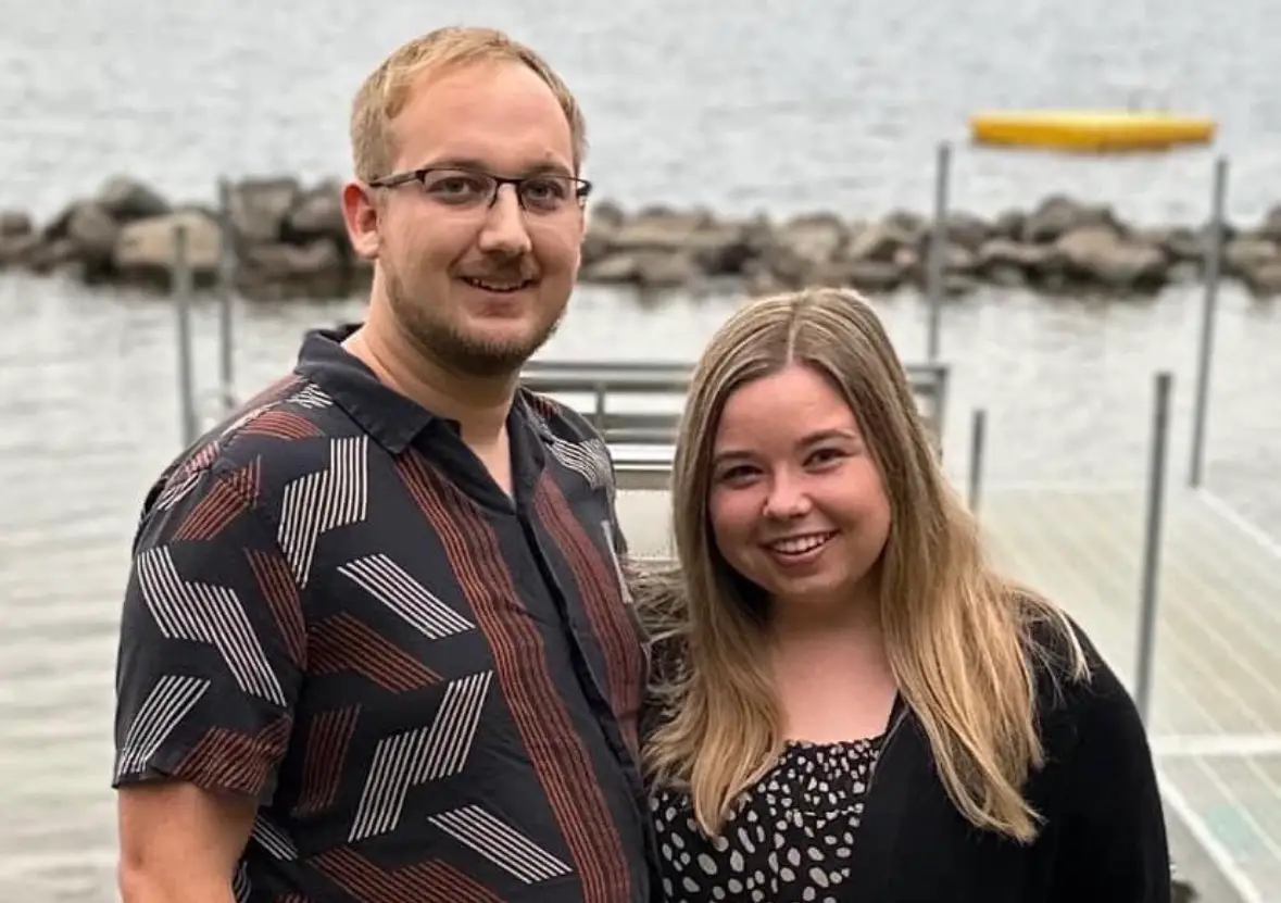 Woman and man smiling in front of water