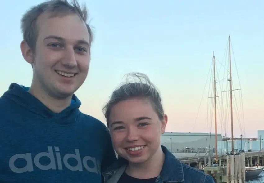 Man and woman smiling in front of pink and blue sky