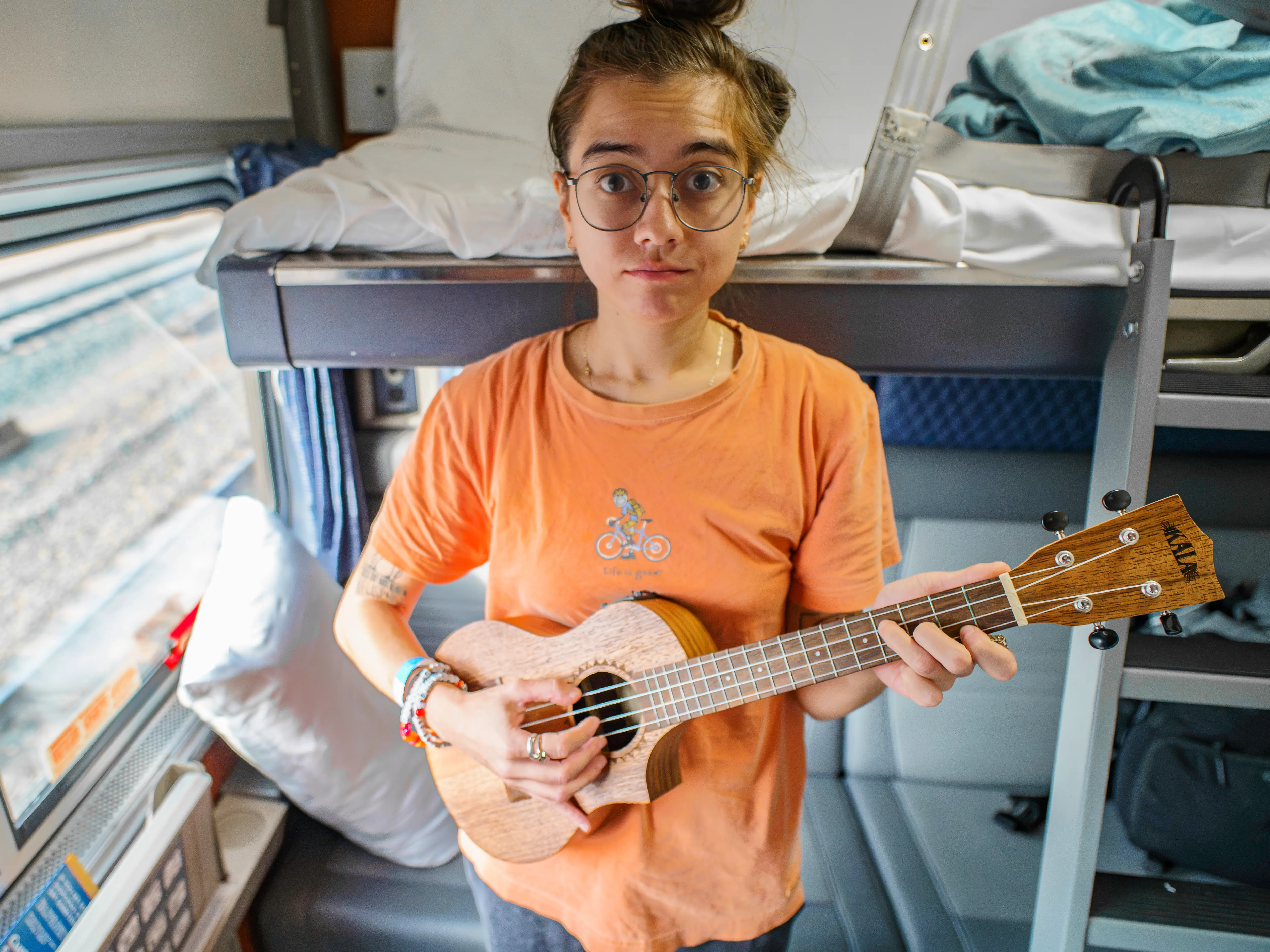 The author holds a ukulele in an Amtrak train bedroom