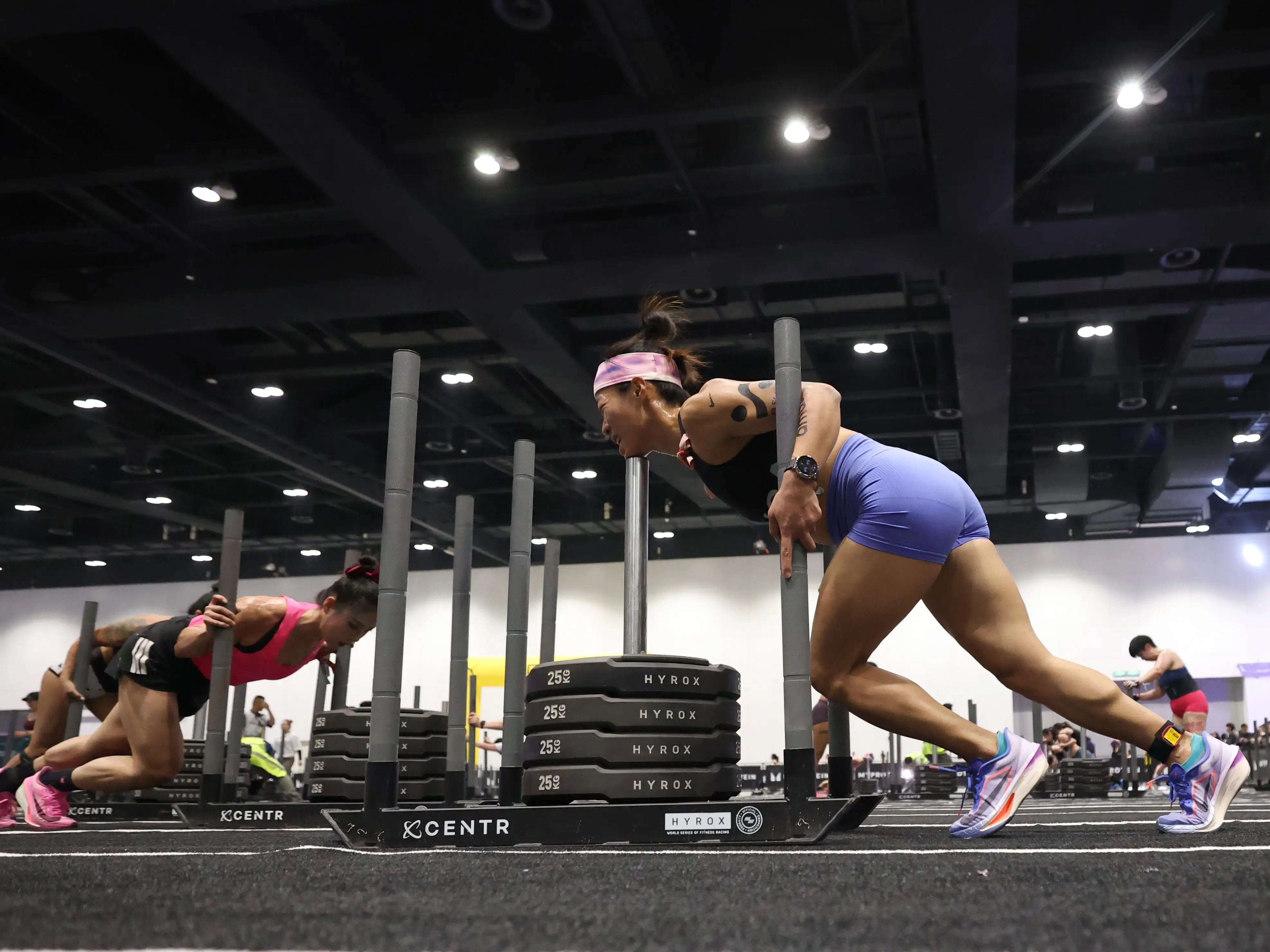 athletes push heavy weighted sleds as part of a Hyrox fitness competition