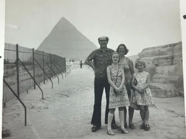 A family of four in a black-and-white photograph standing in front of a pyramid.