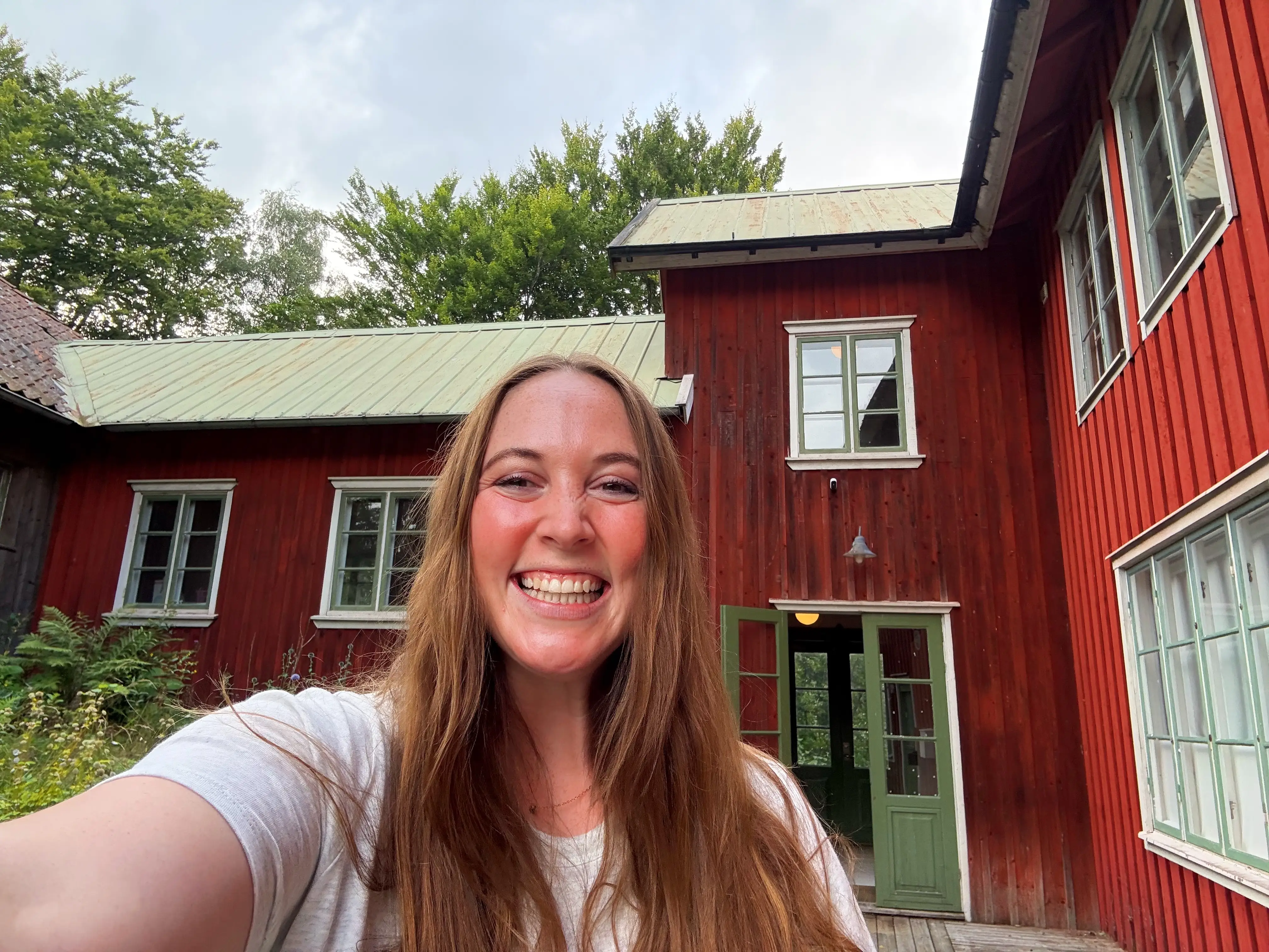 Woman smiling in front of red house with green doors