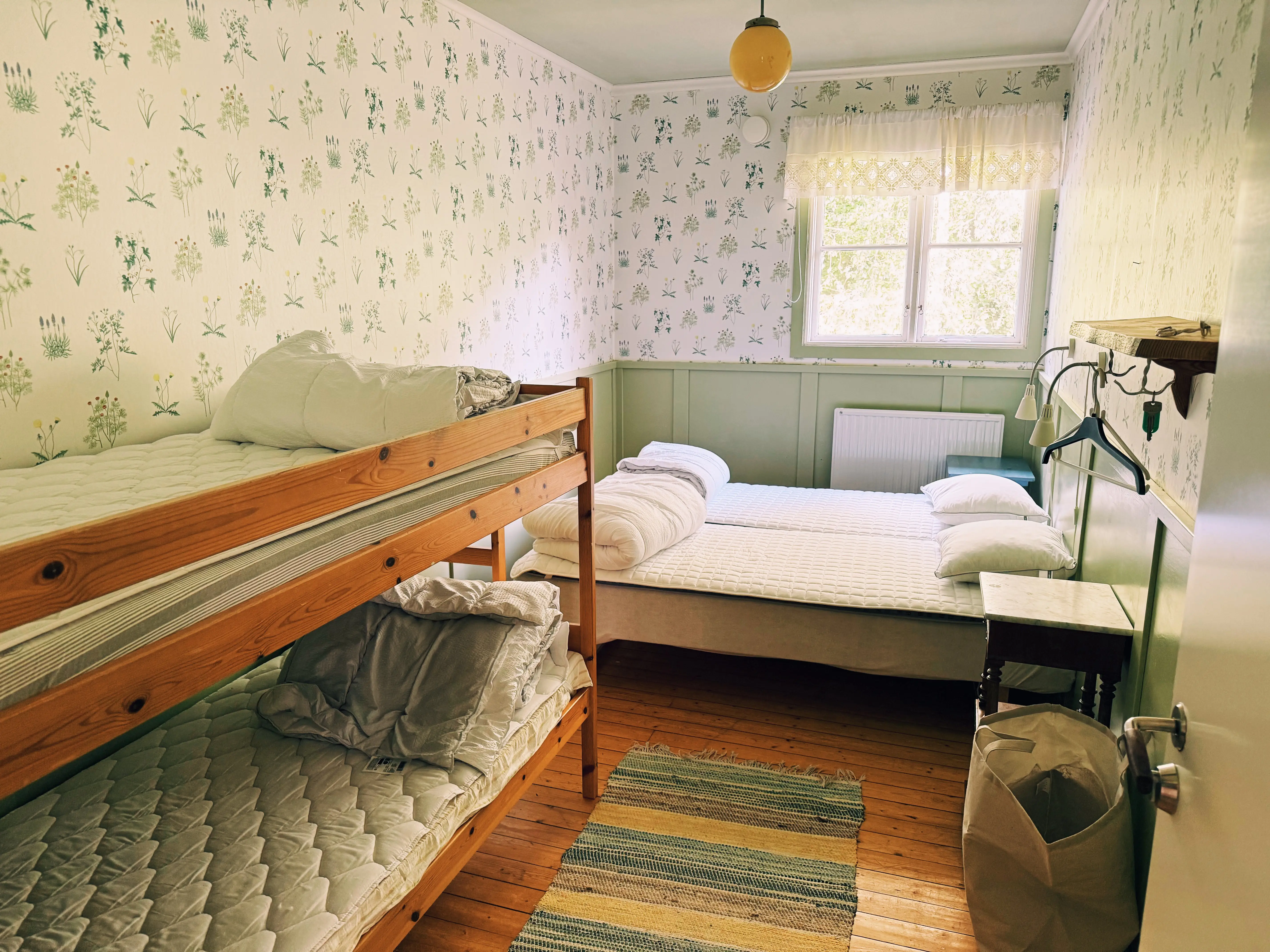 Room with bed and bunk beds and patterned wallpaper