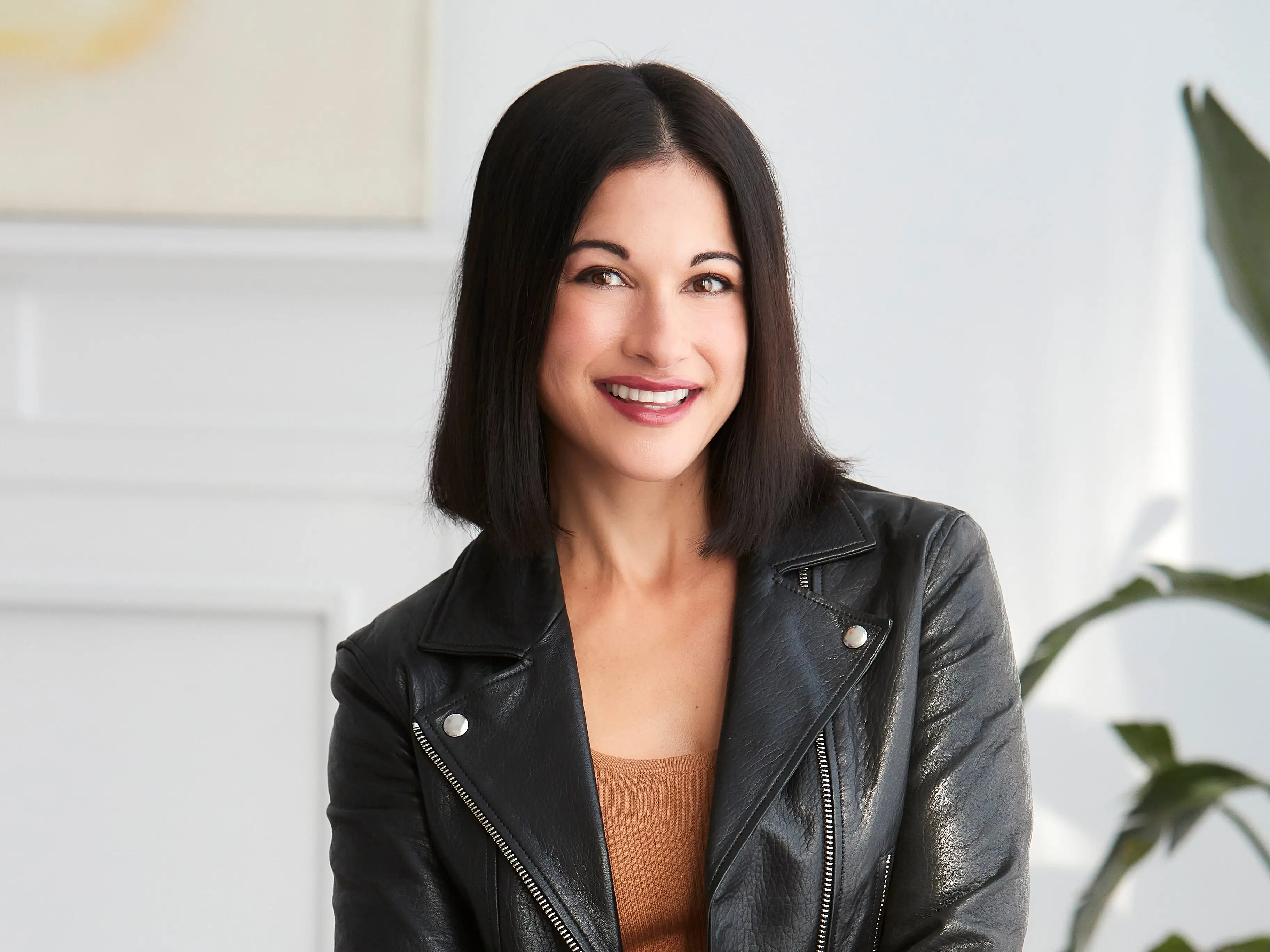headshot of a woman in a brown dress and a leather jacket