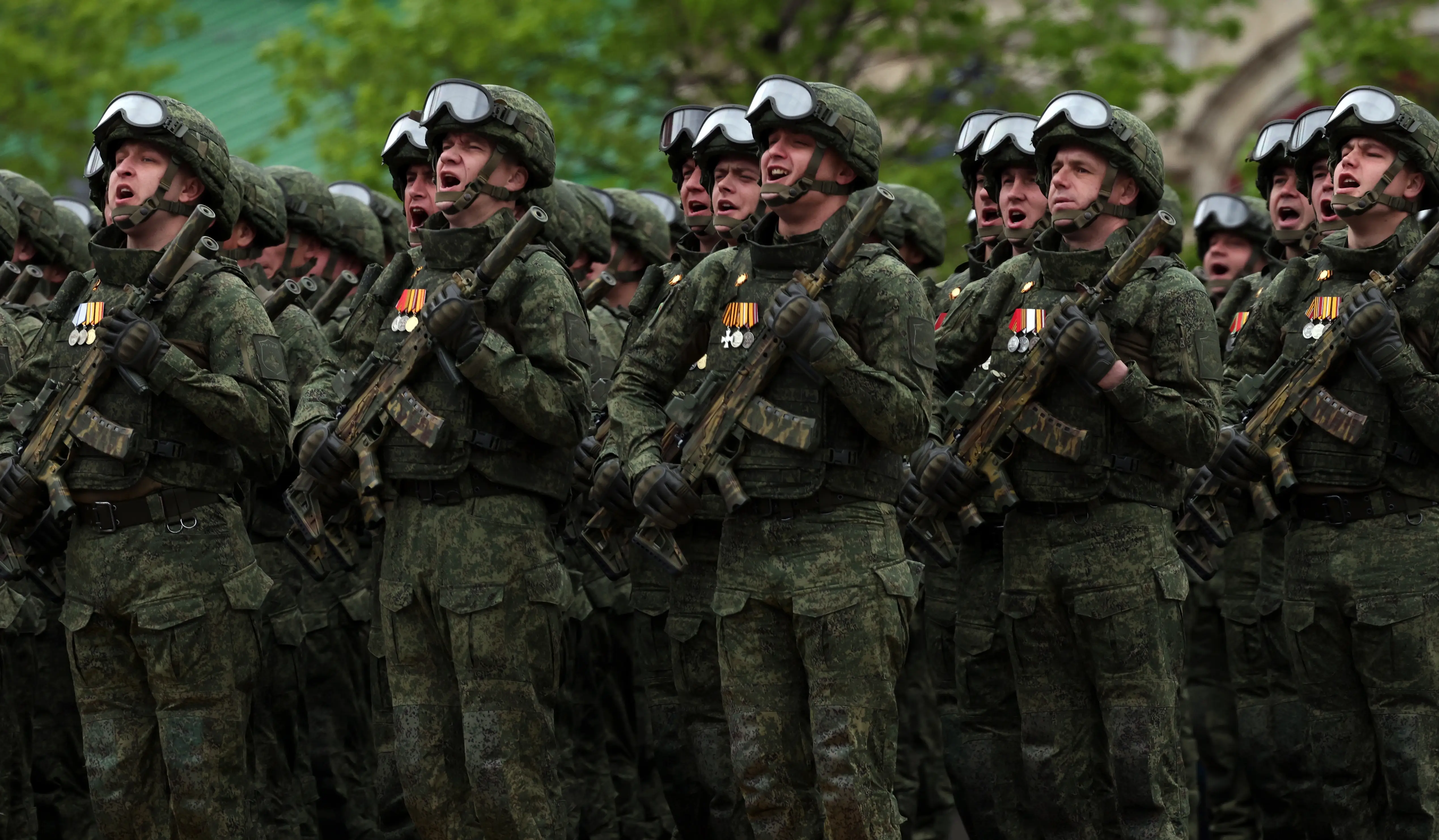 Russian soldiers holding rifles shout.