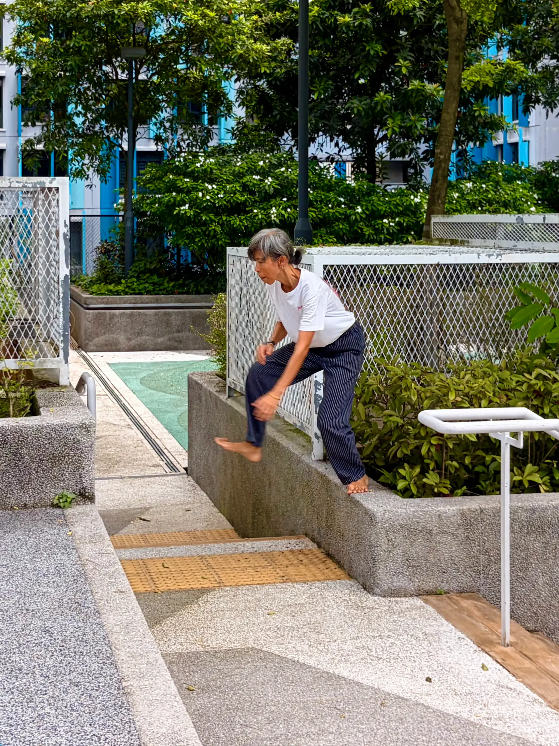 A woman attempting to jump across a ledge.