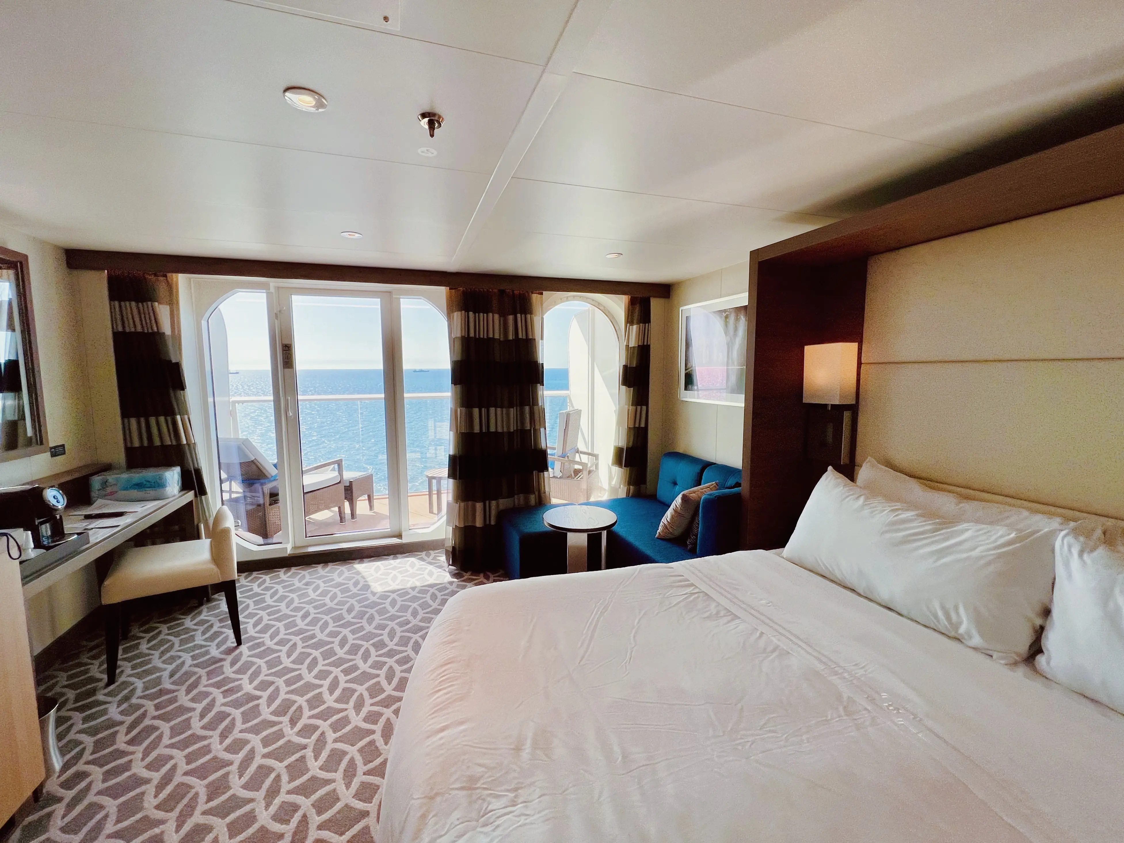 Junior Suite on Odyssey of the Seas with balcony, couch, desk area, bed