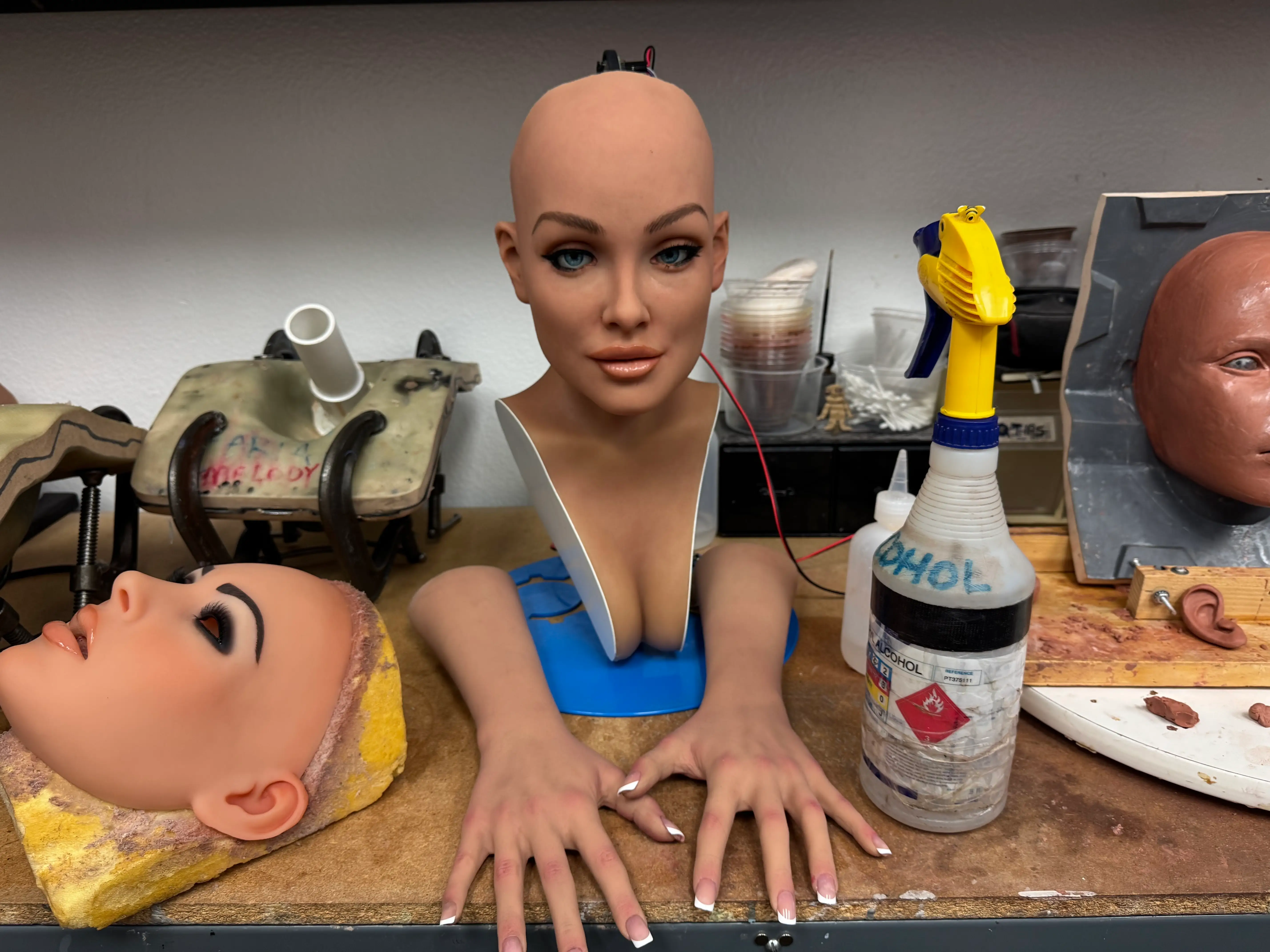 Realbotix robot face and hands on a work station.