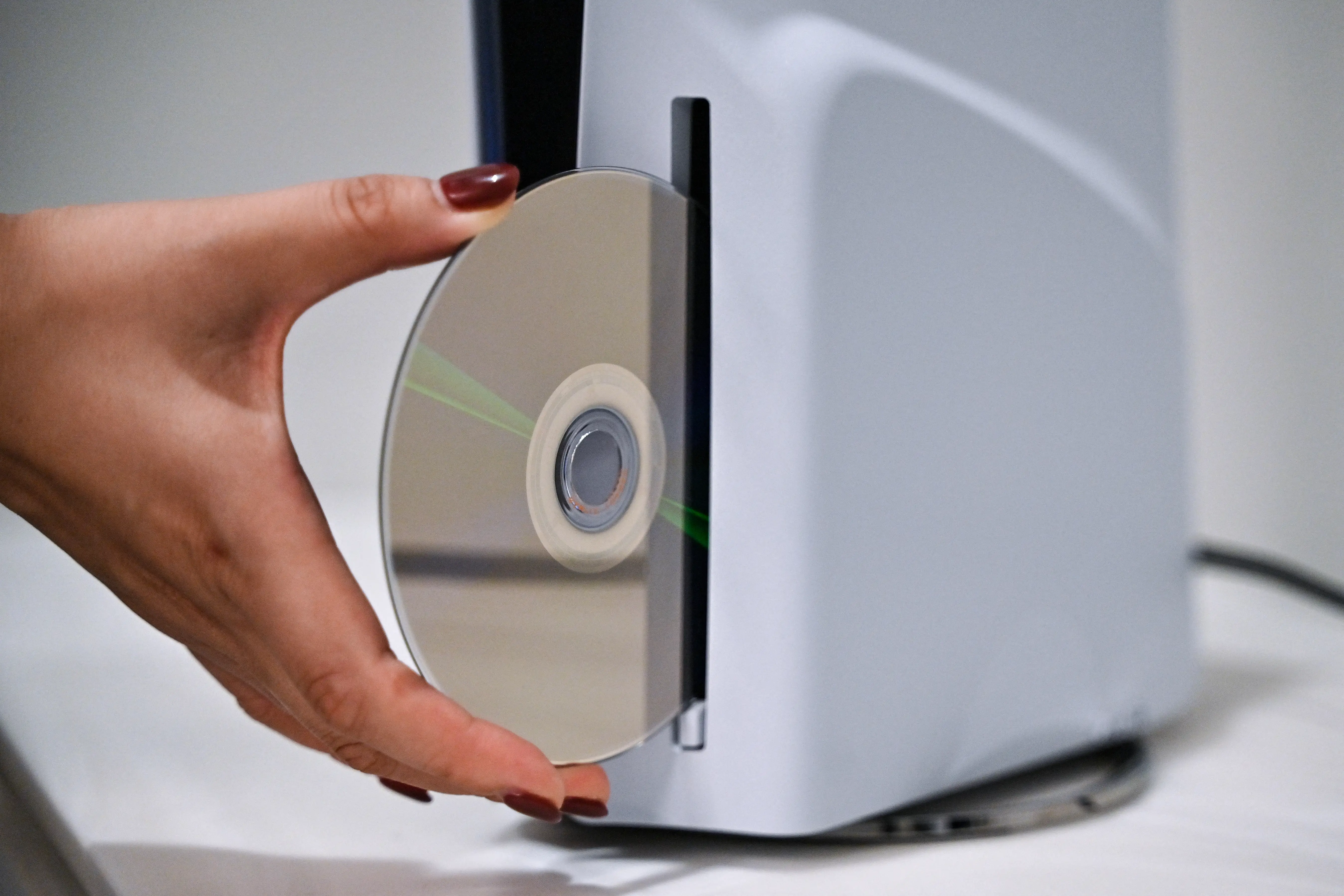 A hand inserts a game disc into a PlayStation 5.