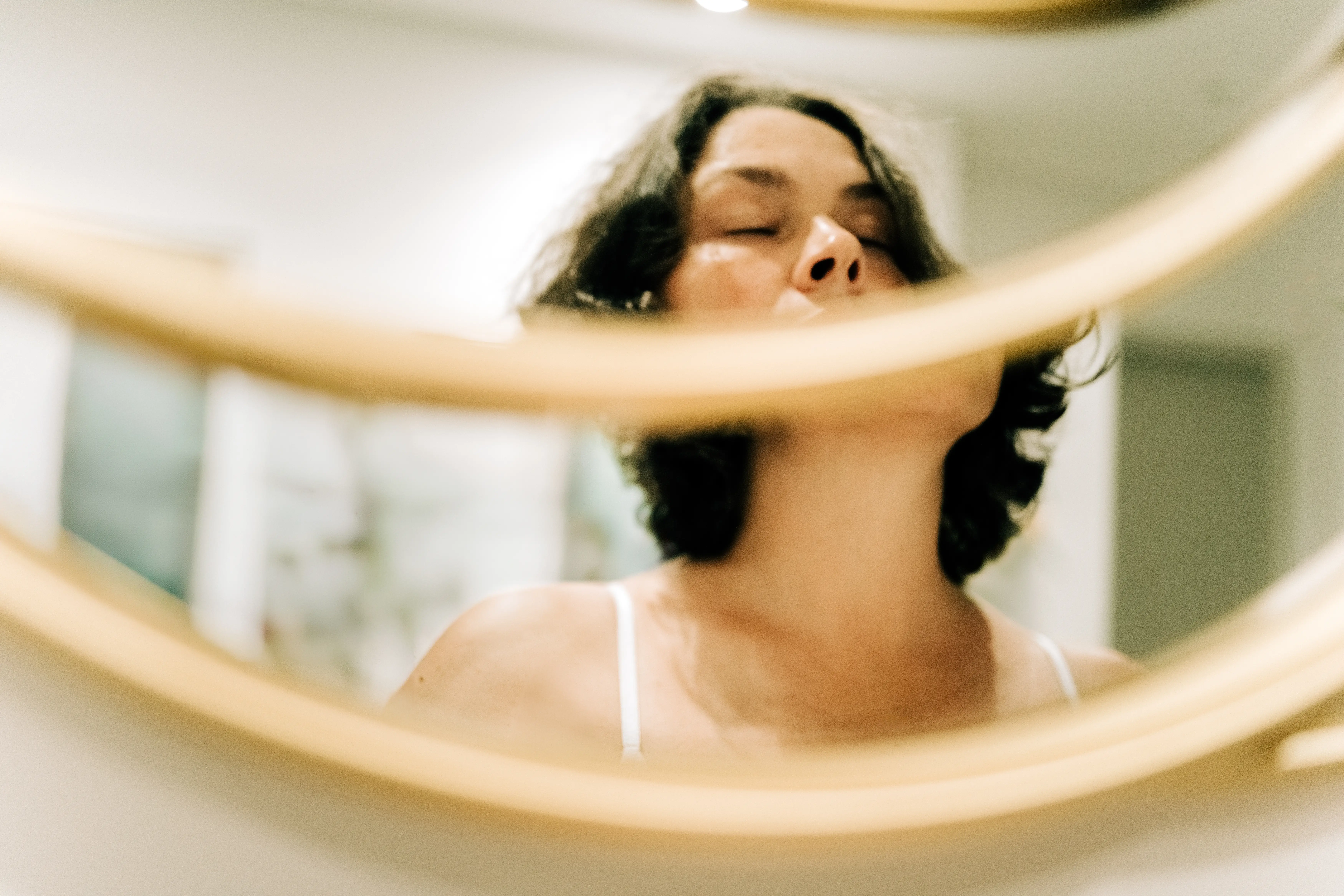 A woman's reflection in a mirror with her eyes closed
