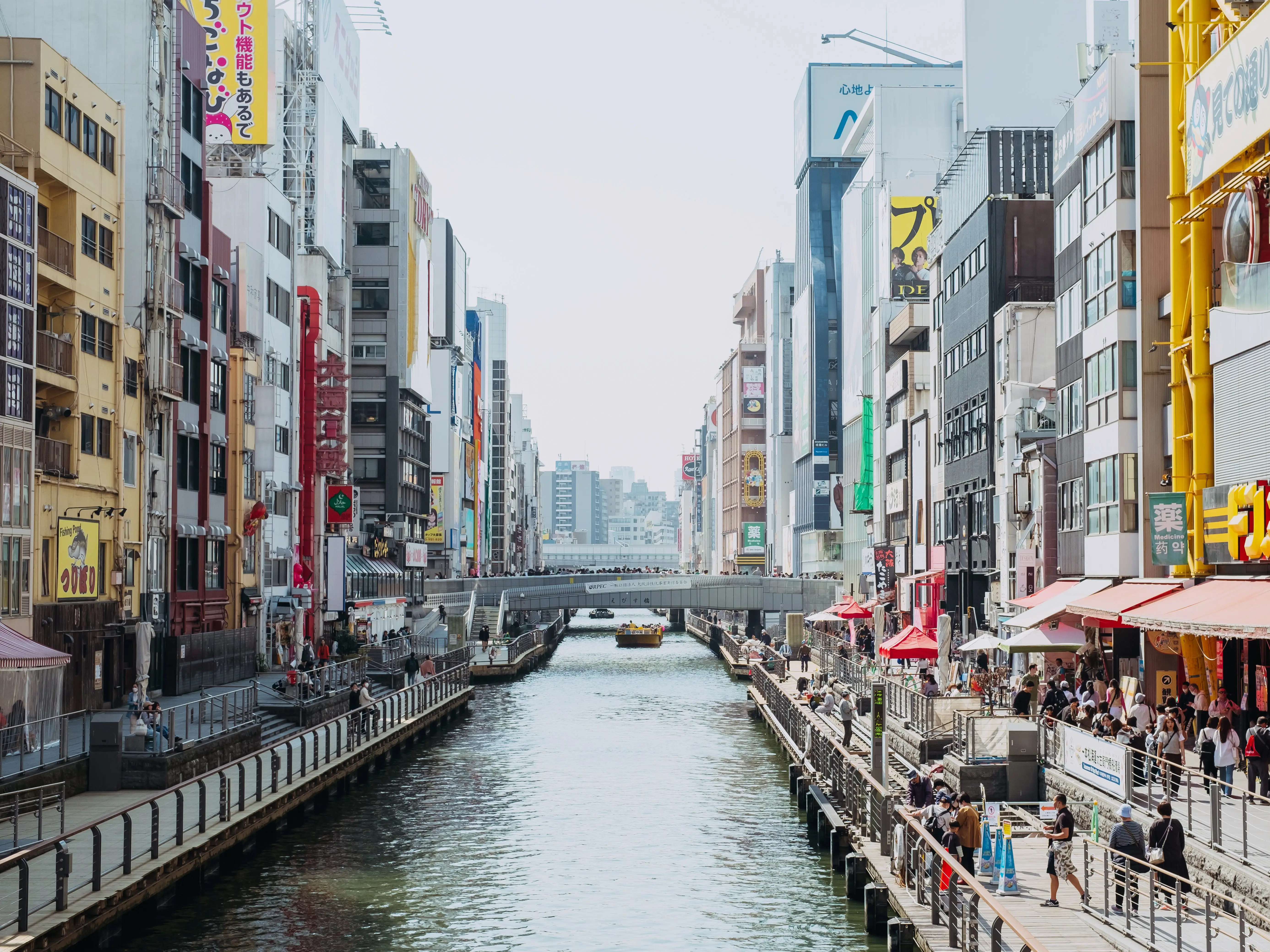 People at Dotonbori canal near buildings and signage in Osaka, Japan.